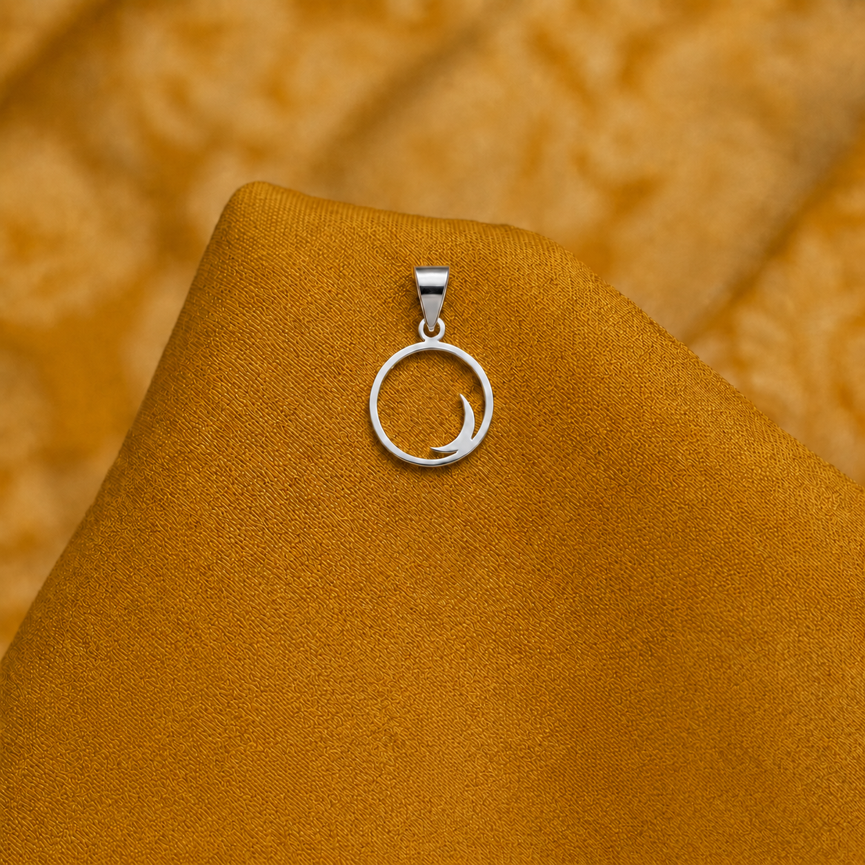 925 silver crescent pendant displayed on plain golden fabric