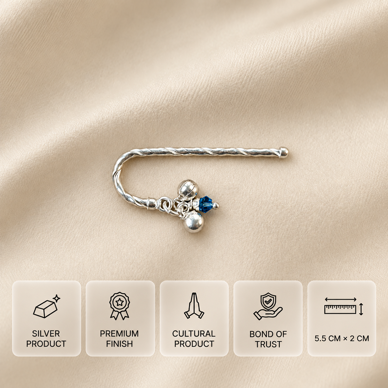 Curved 925 silver flute with two bells and a blue bead on cream fabric, measuring 5.5 × 2 cm.