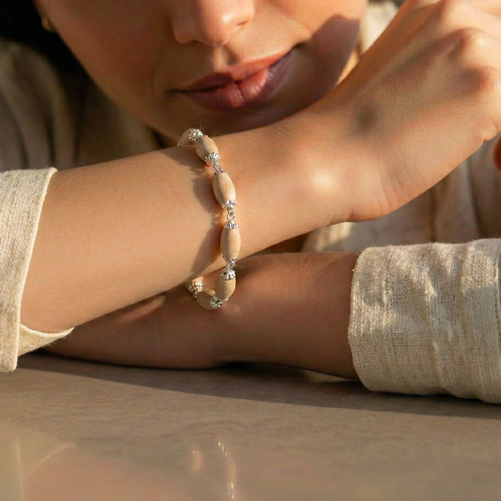 Person wearing a 925 pure silver bracelet with oval Tulsi wood beads and chain design