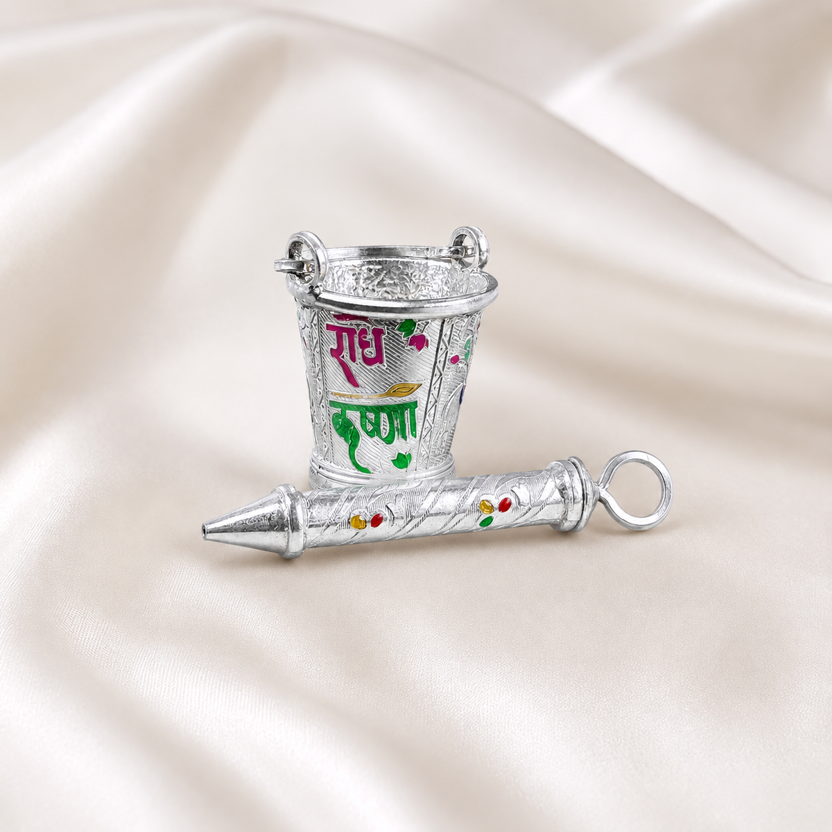 Engraved 925 silver bucket with pink and green Radha Krishna lettering and matching pichkari on cream satin.