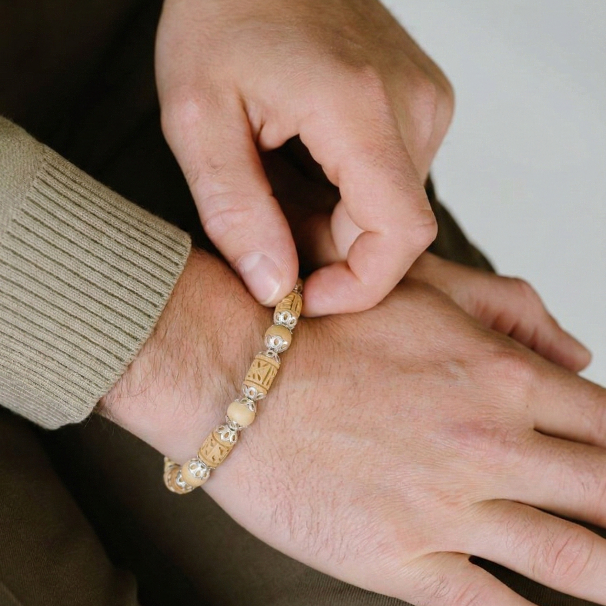 Person wearing a 925 pure silver bracelet featuring Tulsi wood beads with silver caps on wrist