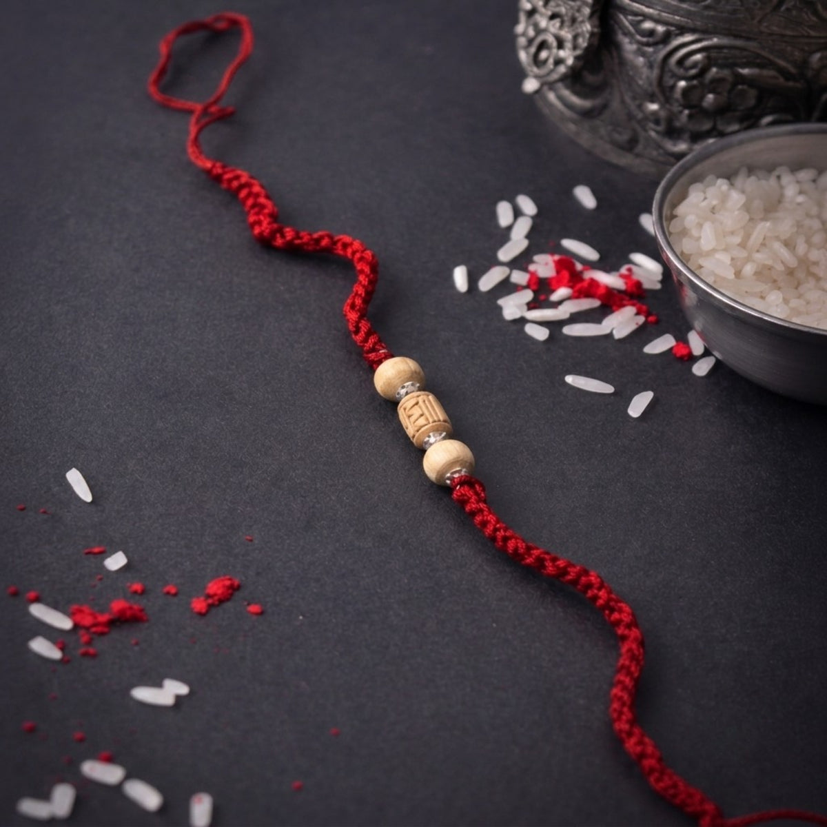 925 pure silver capped carved Tulsi barrel bead sacred rakhi for brother on dark background with pooja rice and silver kalash