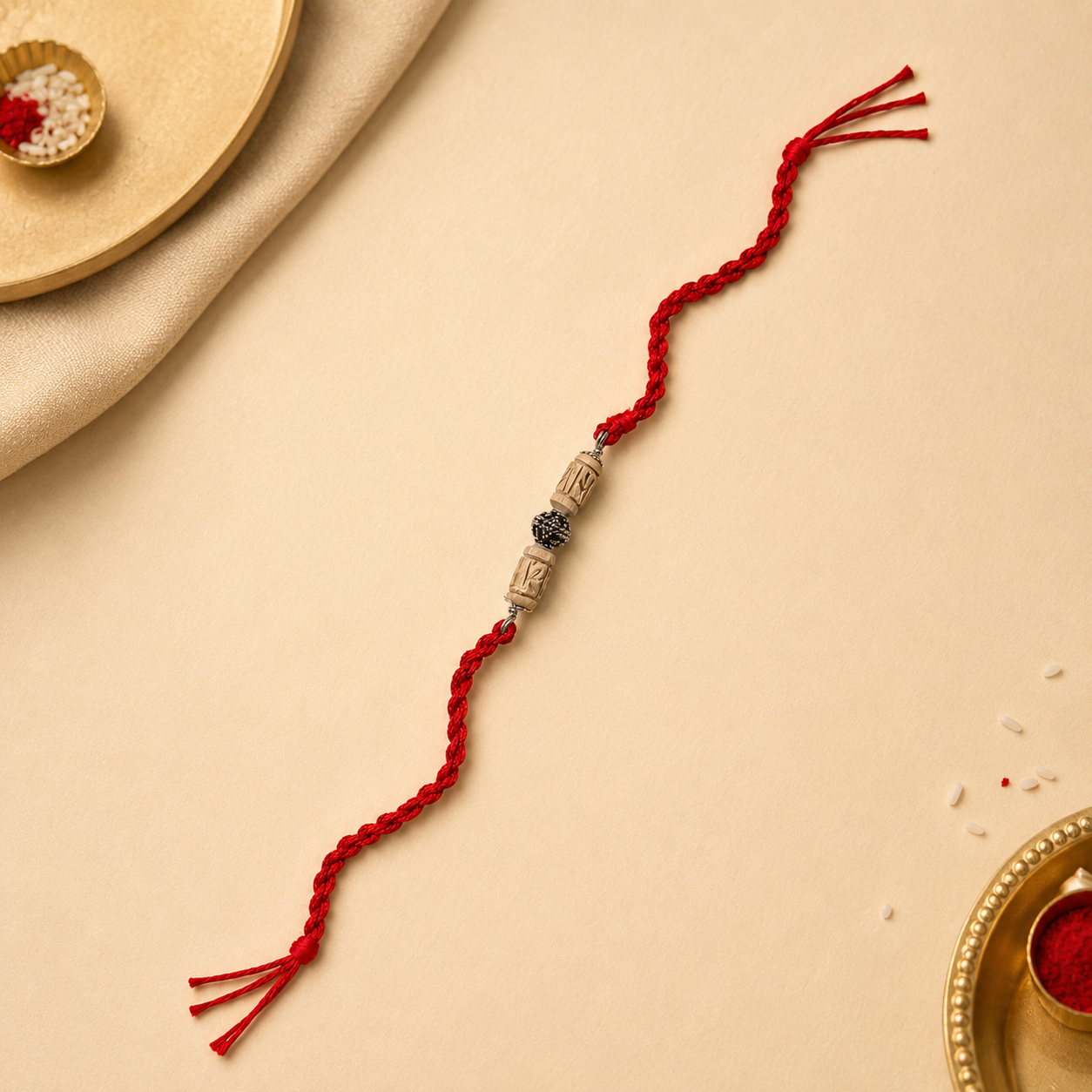 Handcrafted pure silver capped sacred Tulsi bead rakhi on traditional red thread flat lay view