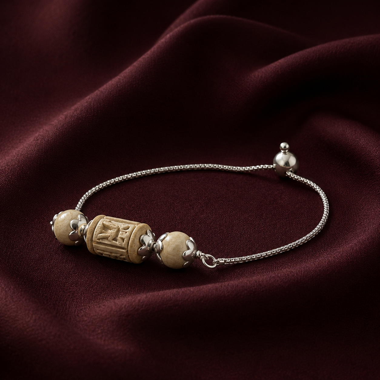 925 pure silver carved Tulsi bead chain bracelet lying on dark maroon silk fabric