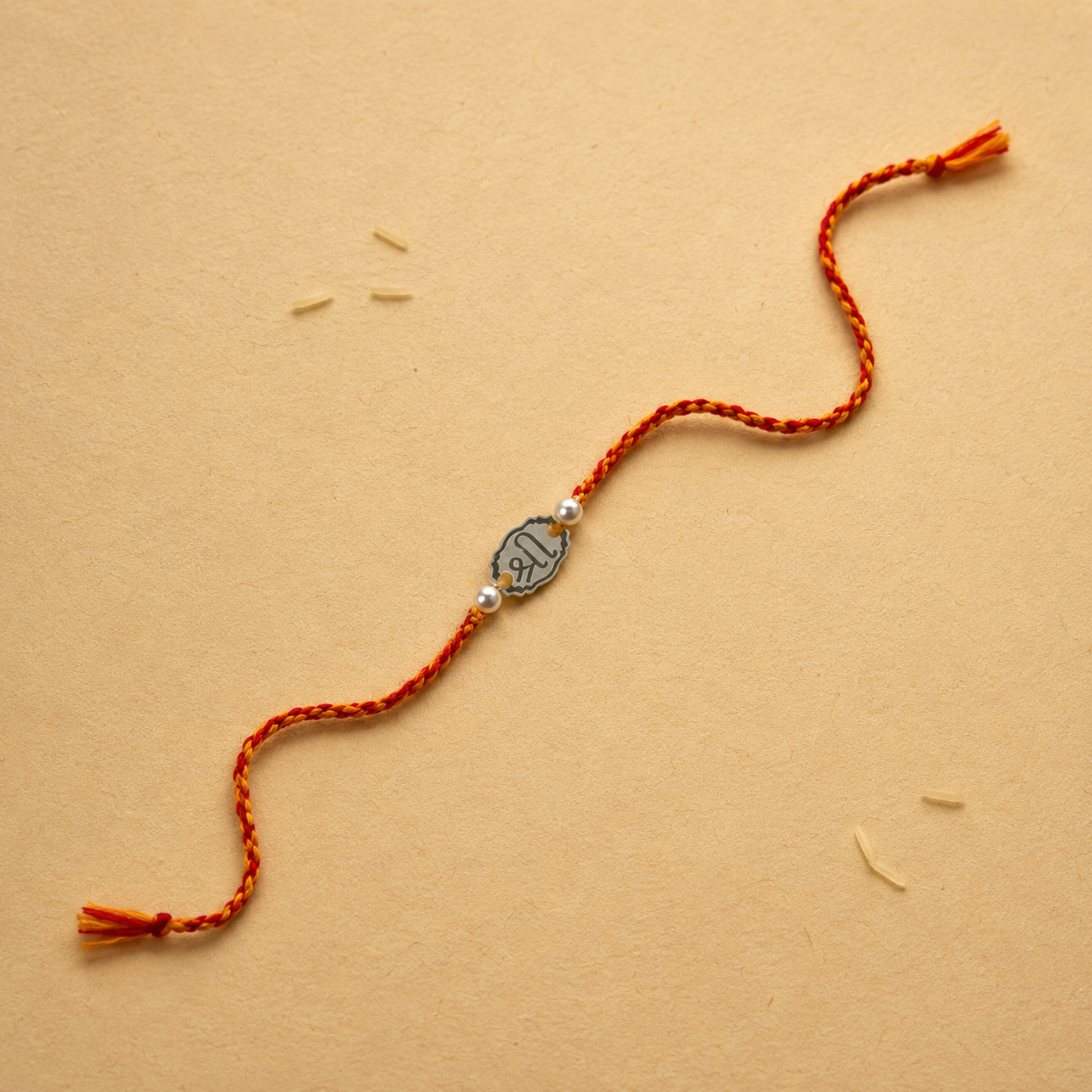 925 pure silver oval Shree charm rakhi with pearl beads on traditional red thread flat lay view