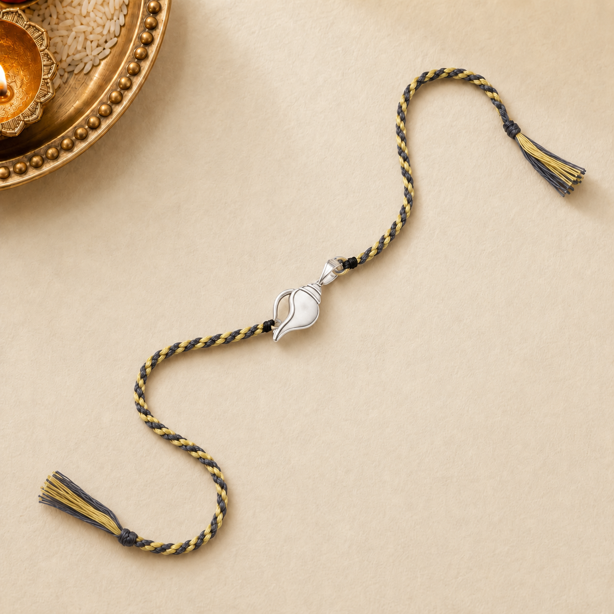 Pure silver Shankh conch shell rakhi on dual tone grey and gold braided thread