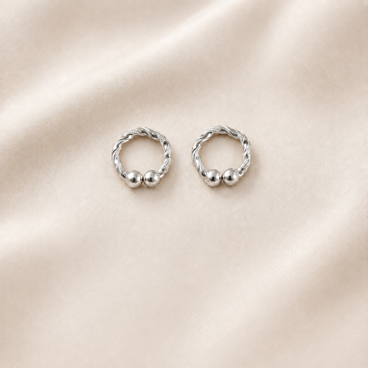 Pair of handcrafted silver kada for deities displayed on soft cream silk backdrop