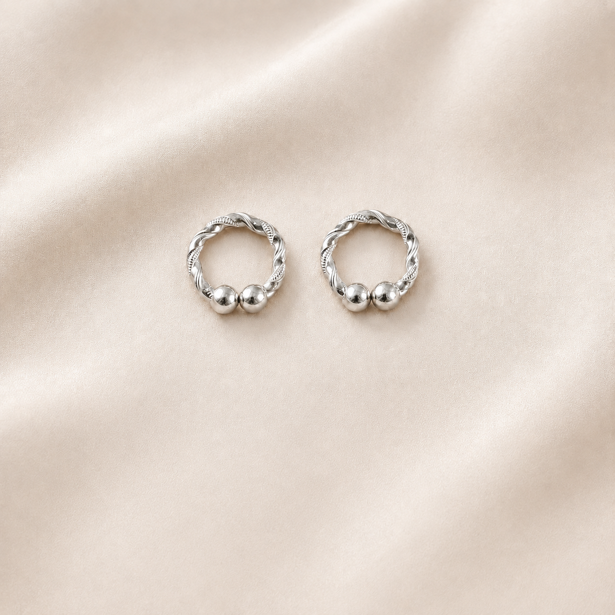 Pair of handcrafted silver kada for deities displayed on soft cream silk backdrop