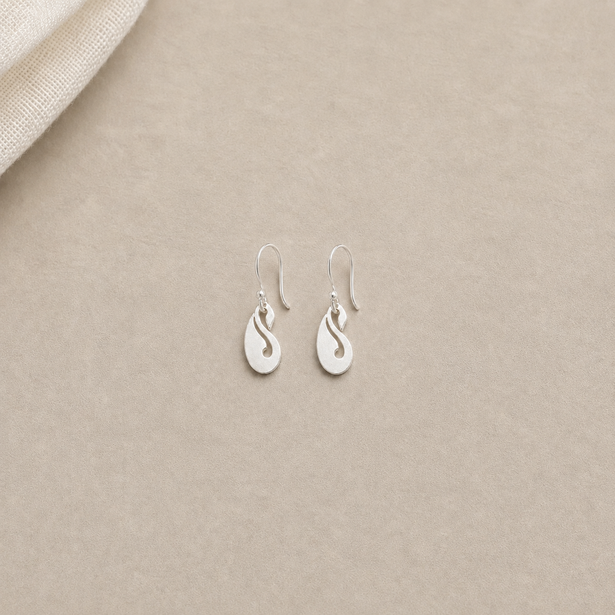 925 sterling silver peacock drop wire hook earrings displayed on light sand textured fabric