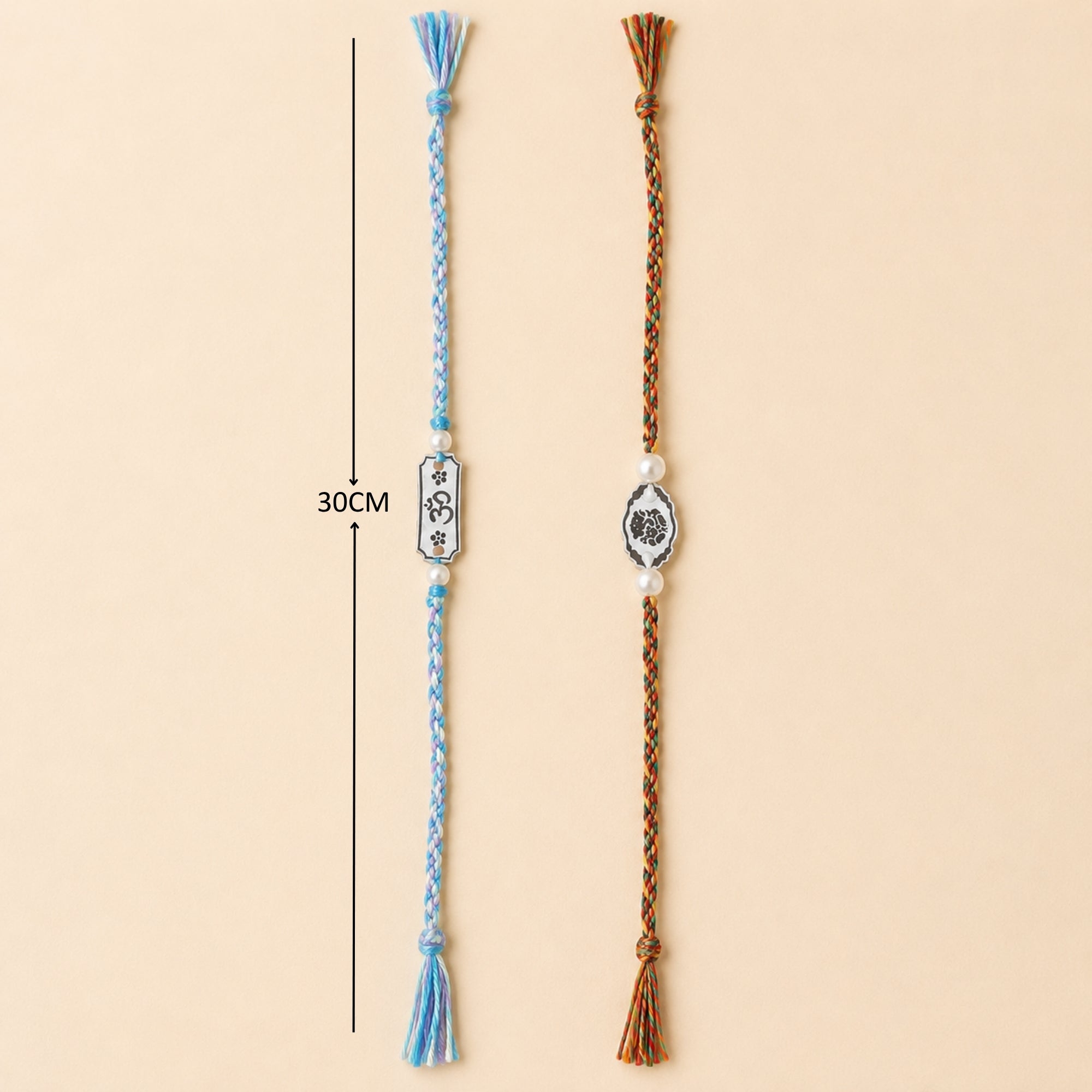 Two 925 sterling silver Subh Om Labh and Ganesha charm rakhis with pearl beads laid out vertically