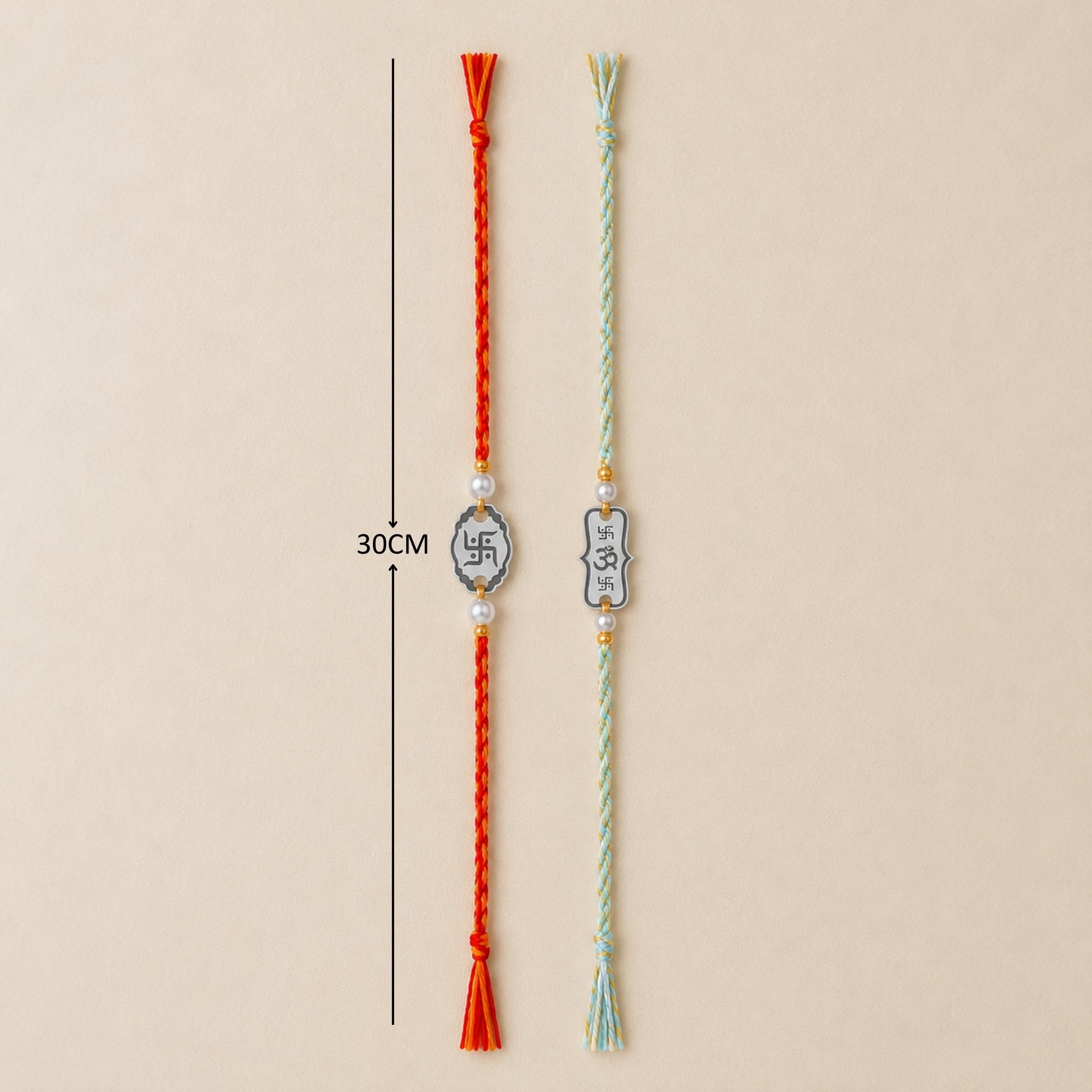 Two 925 sterling silver Subh Om Labh frame and Om charm rakhis with pearl beads laid out vertically