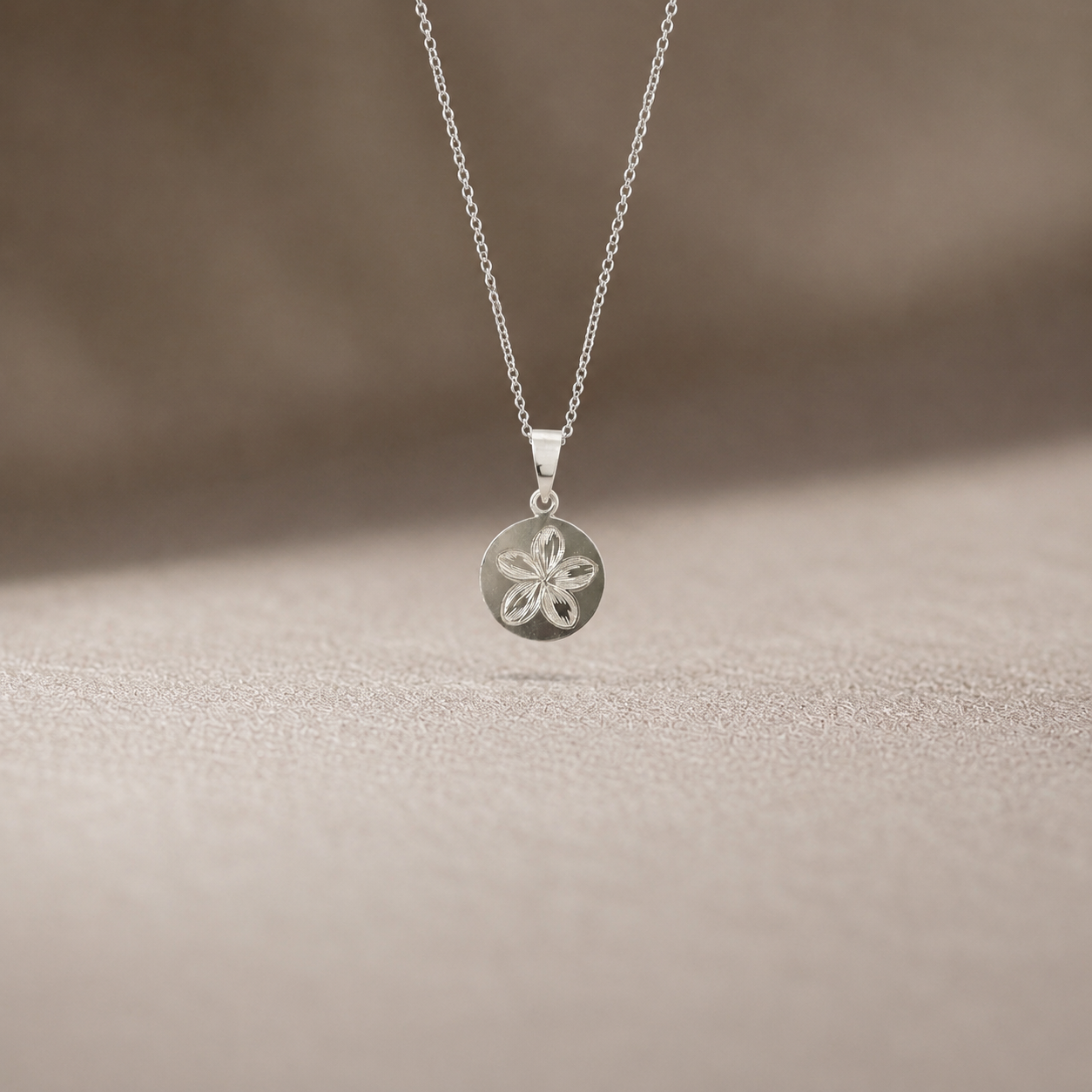 925 sterling silver engraved floral disc pendant for men and women displayed on soft textured fabric