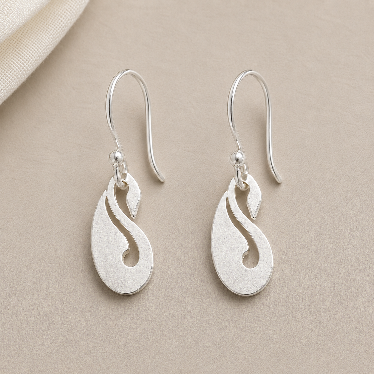 925 sterling silver peacock drop wire hook earrings displayed on light sand textured fabric