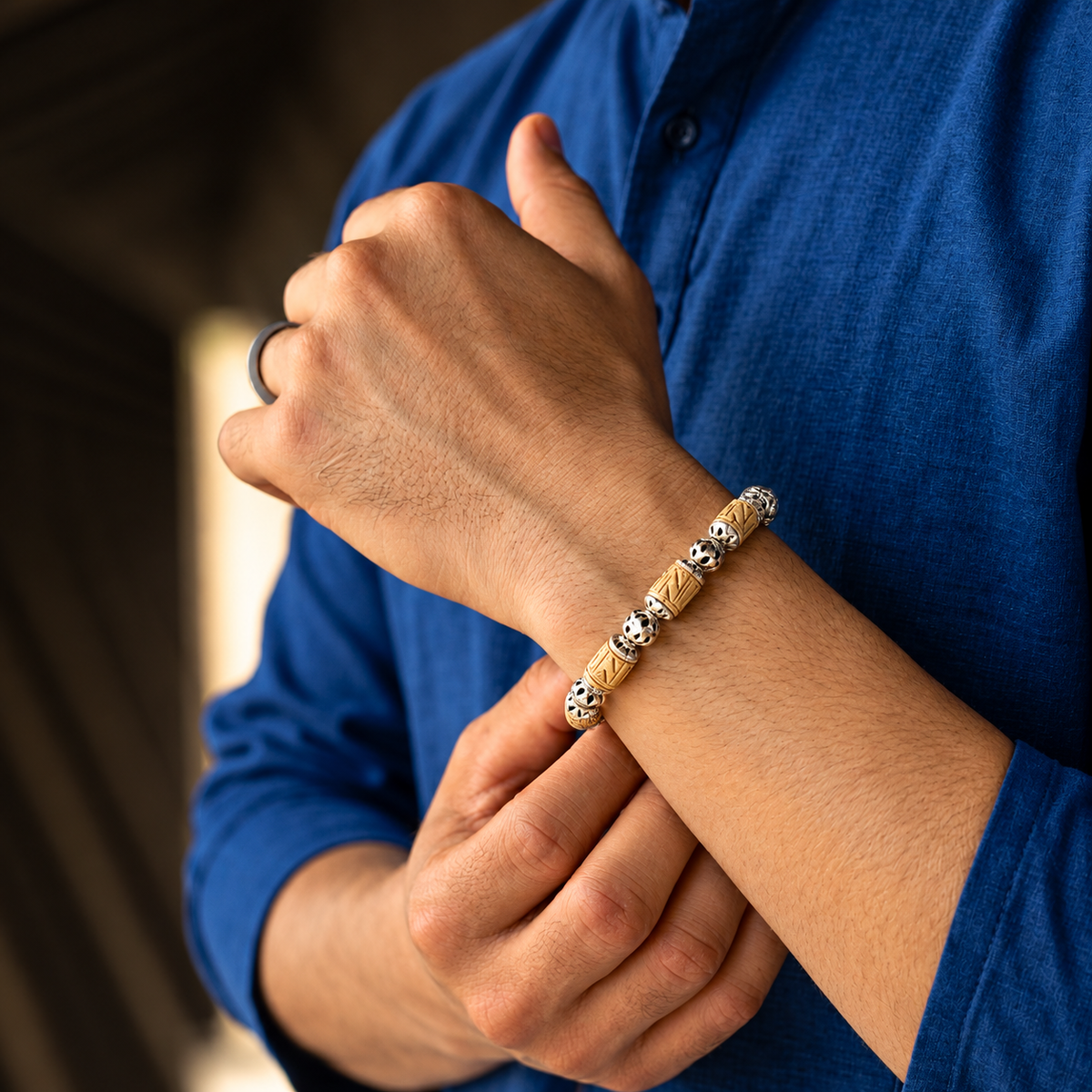 Handcrafted carved bead bracelet with silver accents worn on the wrist