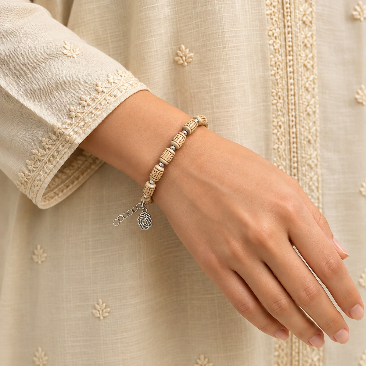 Handcrafted wooden bead bracelet with carved beige beads, silver spacers and a feather charm