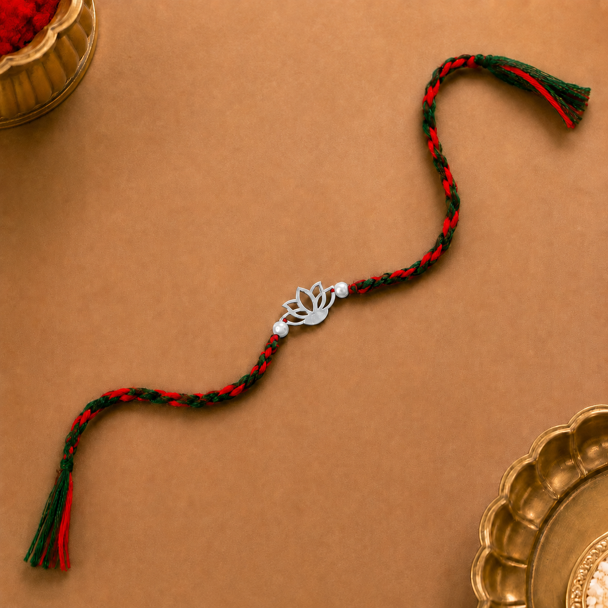 Silver Lotus Rakhi with pearl-style beads and red-green braided thread