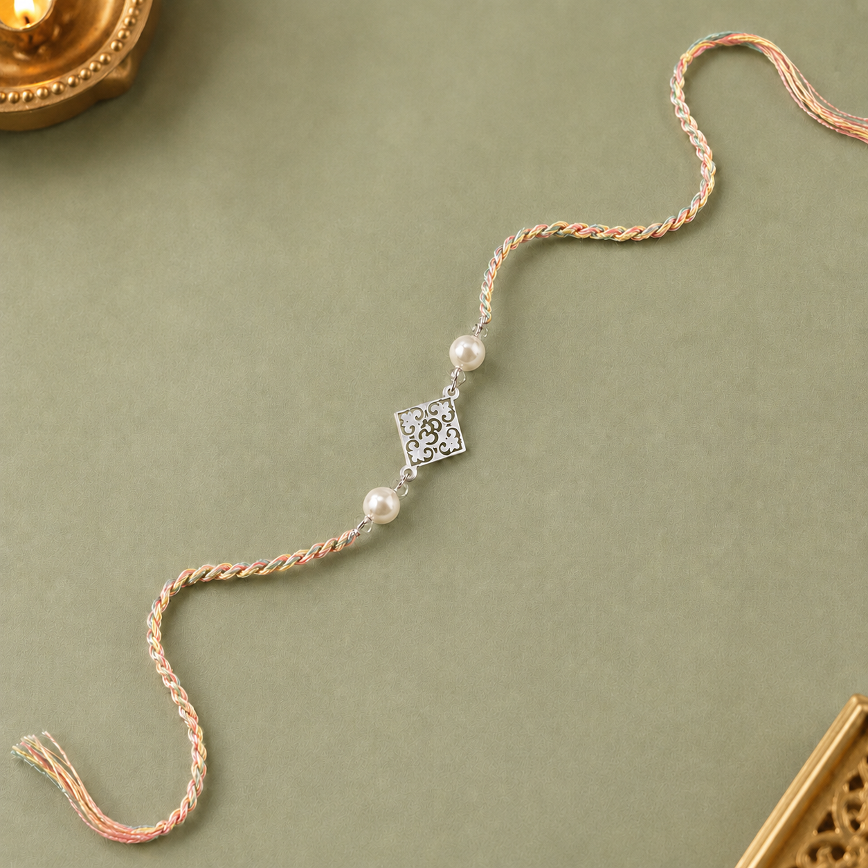 Designer silver Om Rakhi for brother with pearl beads and pastel braided thread
