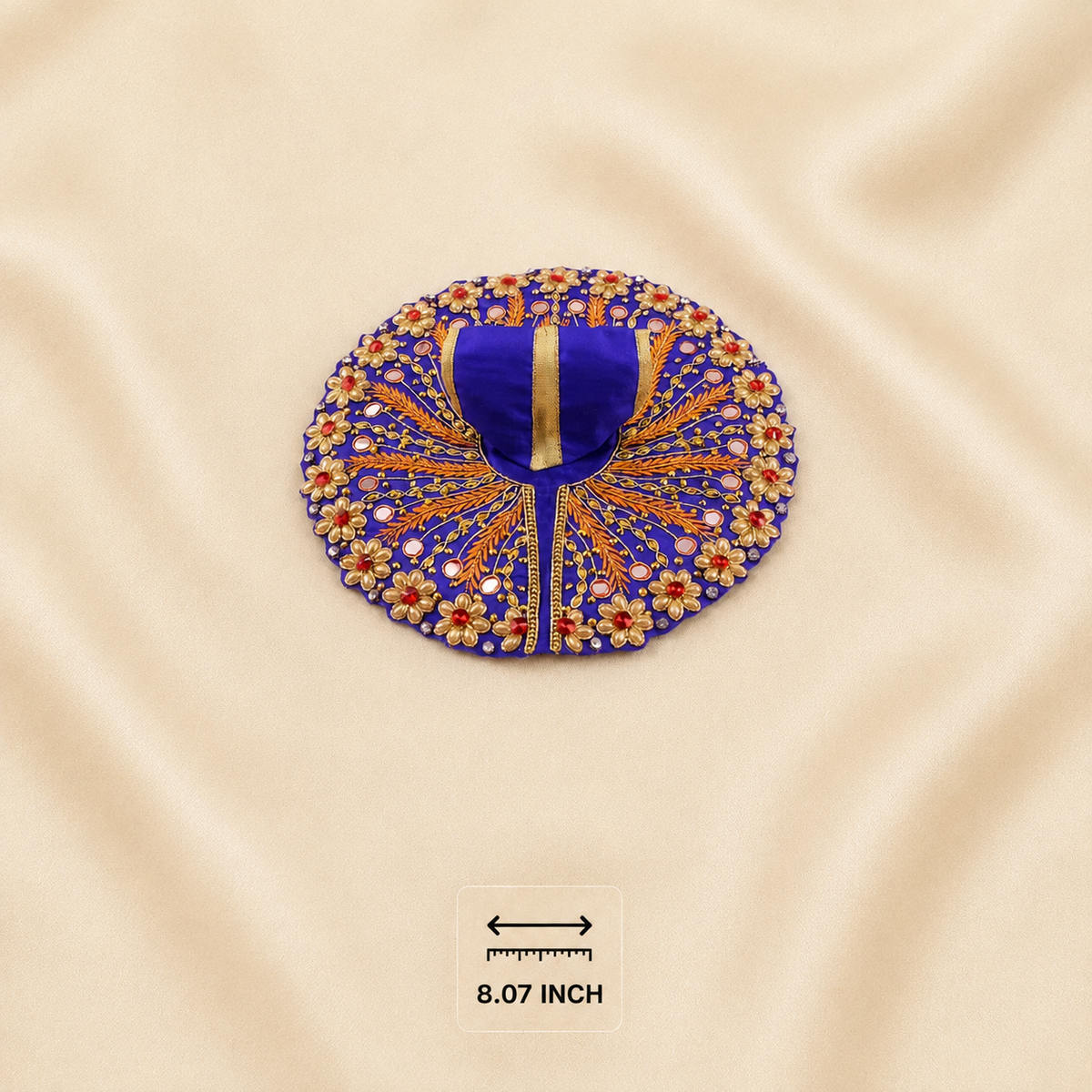 A circular royal blue embroidered poshak with gold and red floral detailing, displayed on a beige satin fabric background with an '8.07 INCH' size marker below.