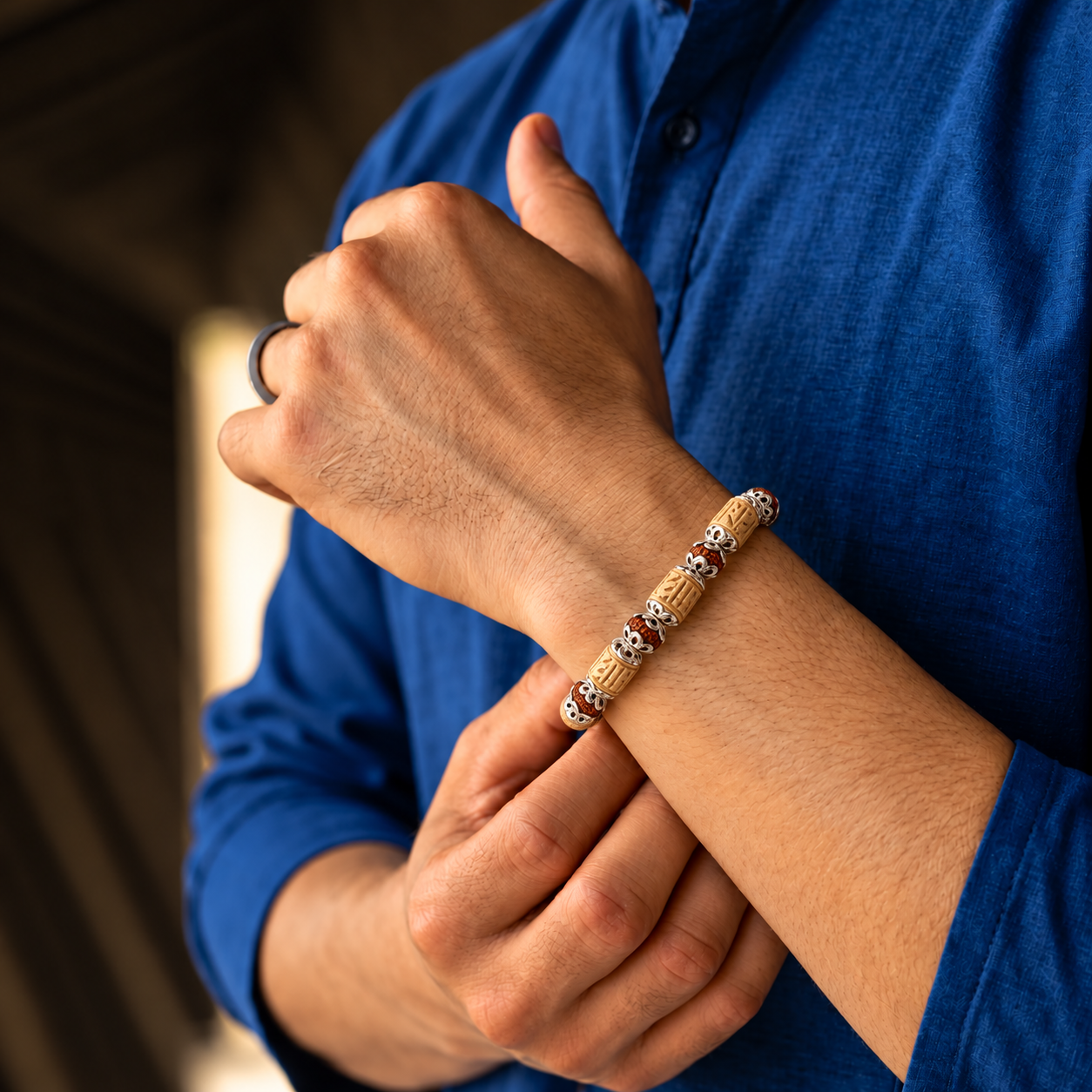 Handcrafted carved rudraksha bead bracelet with silver accents worn on the wrist