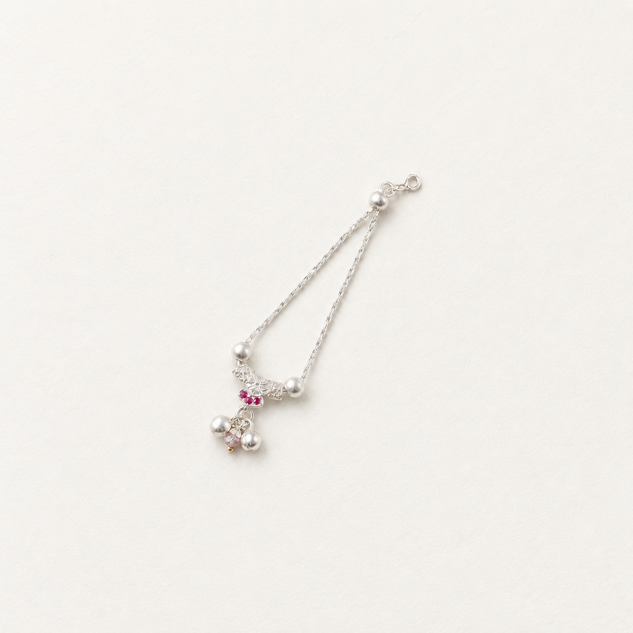Pure silver necklace for deity idols with pink stones and pearl drops on off-white background.