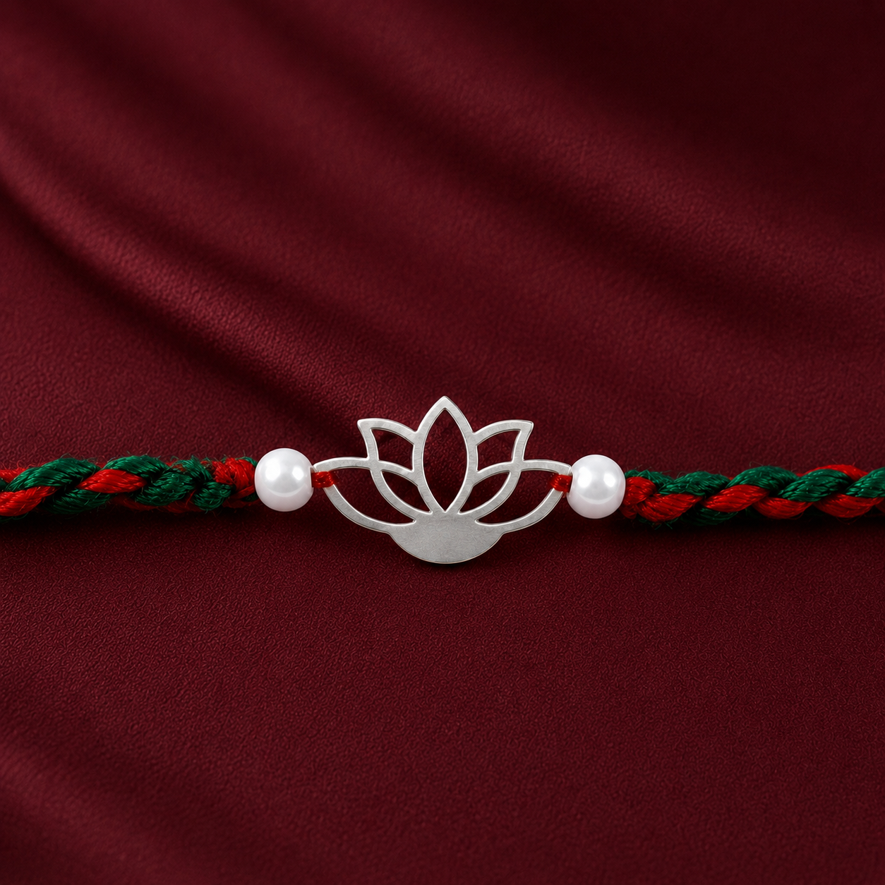 Close-up of openwork silver lotus charm with two pearl-style beads and braided thread