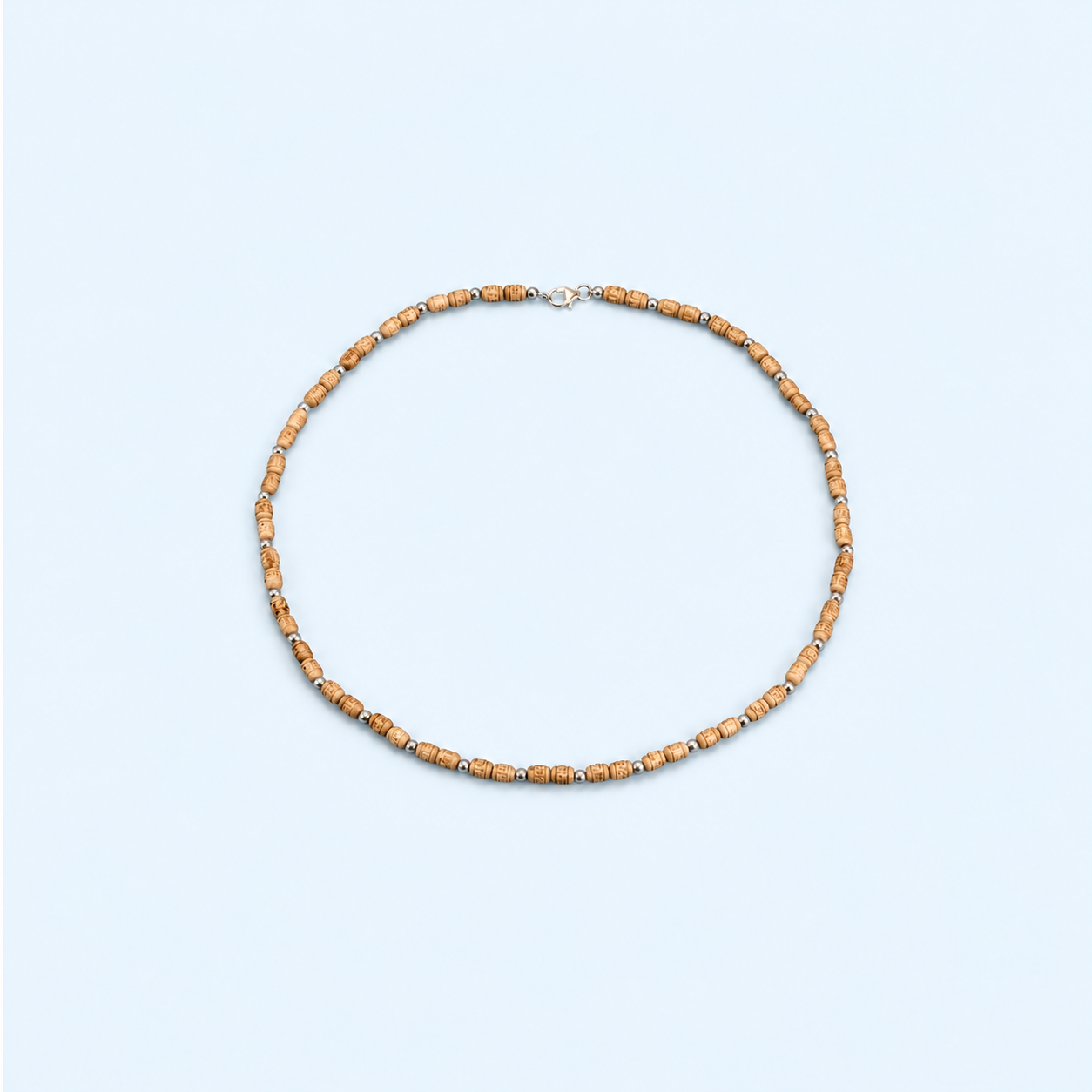 Tulsi mala with carved wooden beads, silver-tone spacers and a clasp, arranged on a pastel blue background.