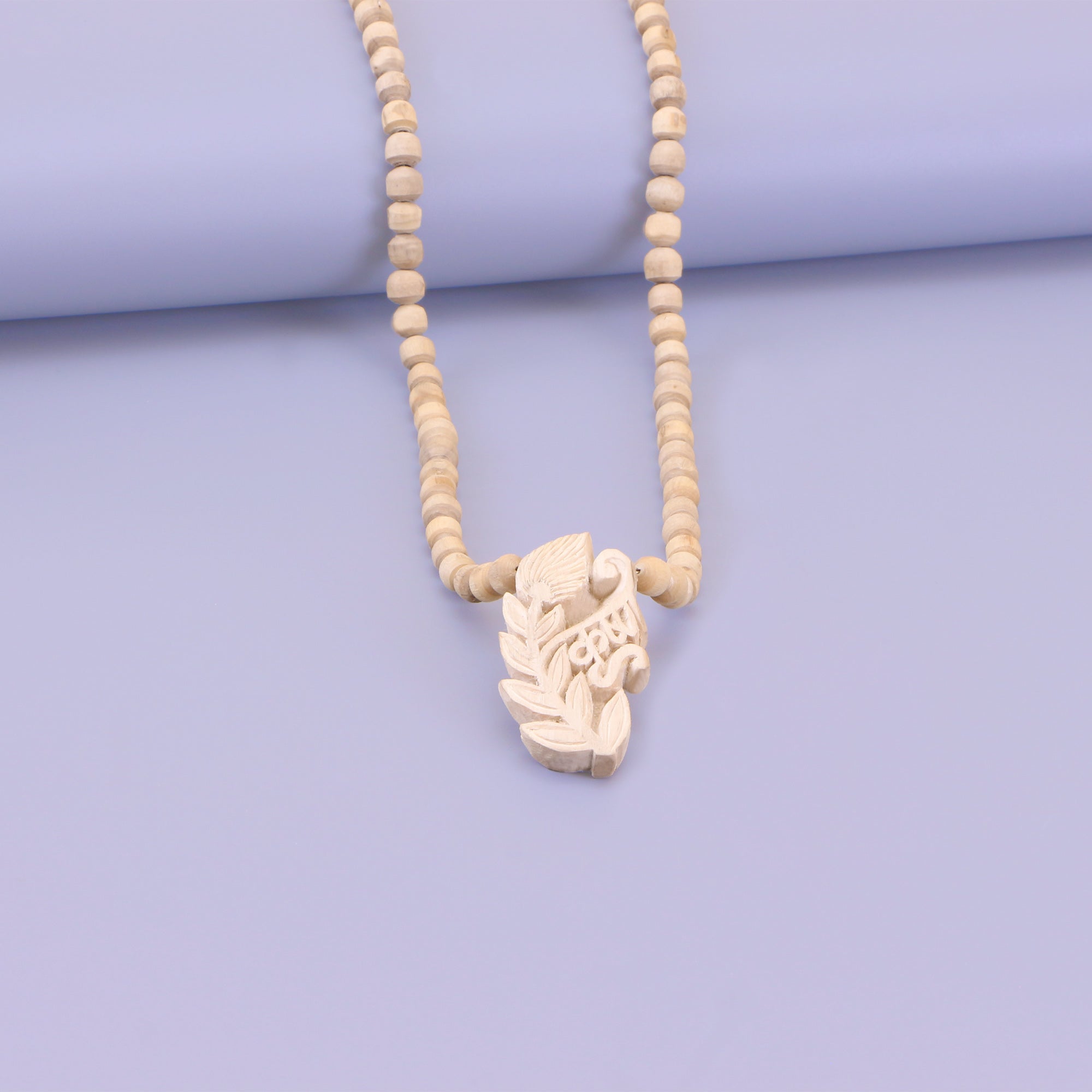 Close up of an exquisite hand-carved wooden Lord Krishna pendant on a pure Tulsi mala