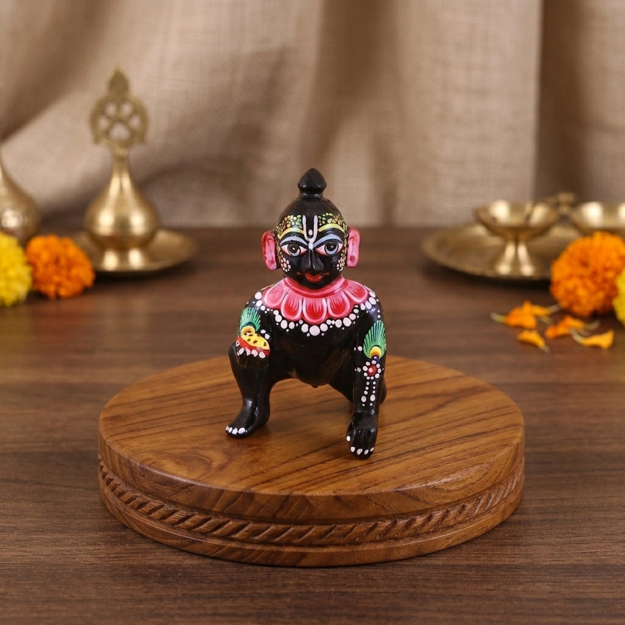 Black brass Laddu Gopal idol with big eyes displayed on a traditional wooden stand