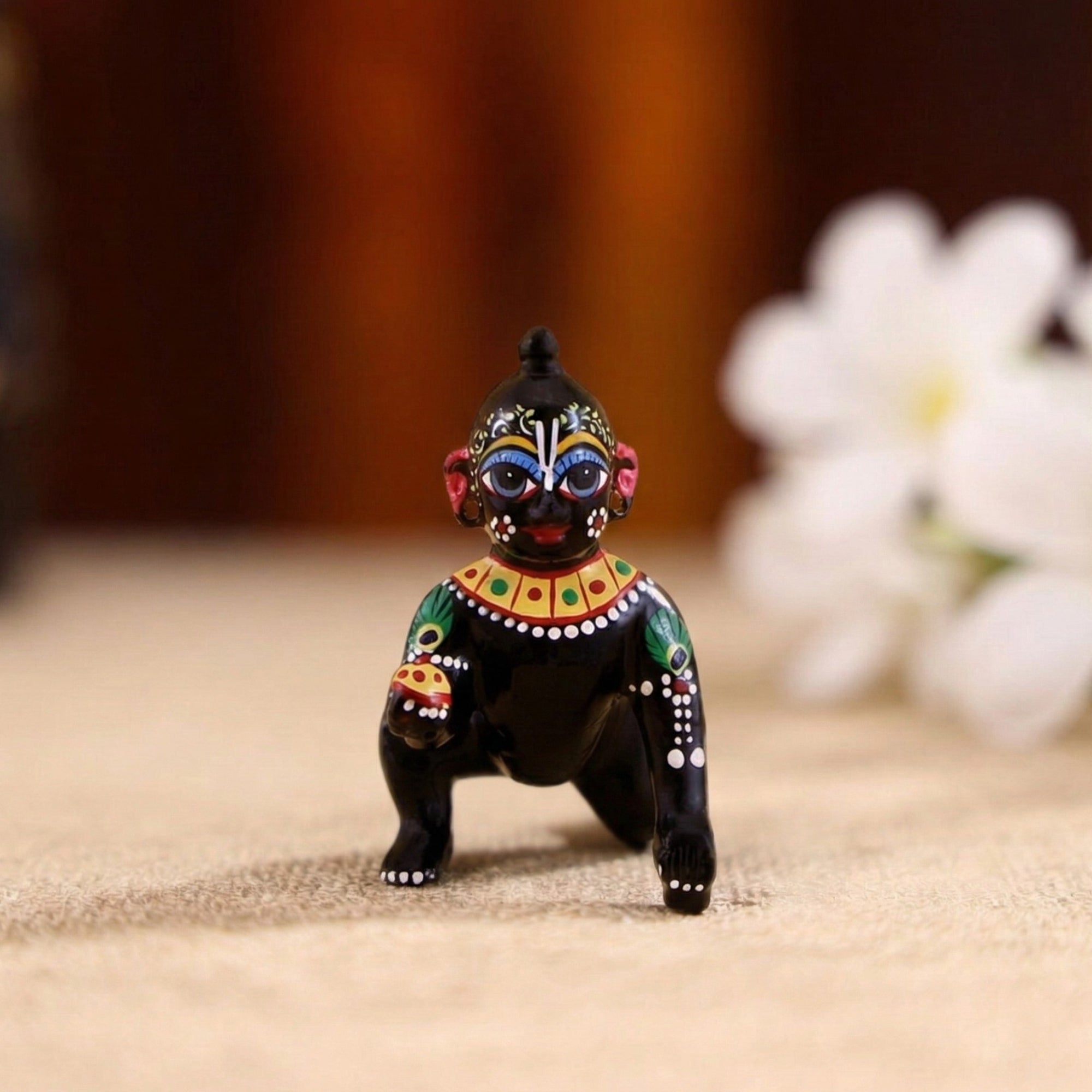 Front view of a hand-painted black brass Laddu Gopal idol with intricate traditional decorations