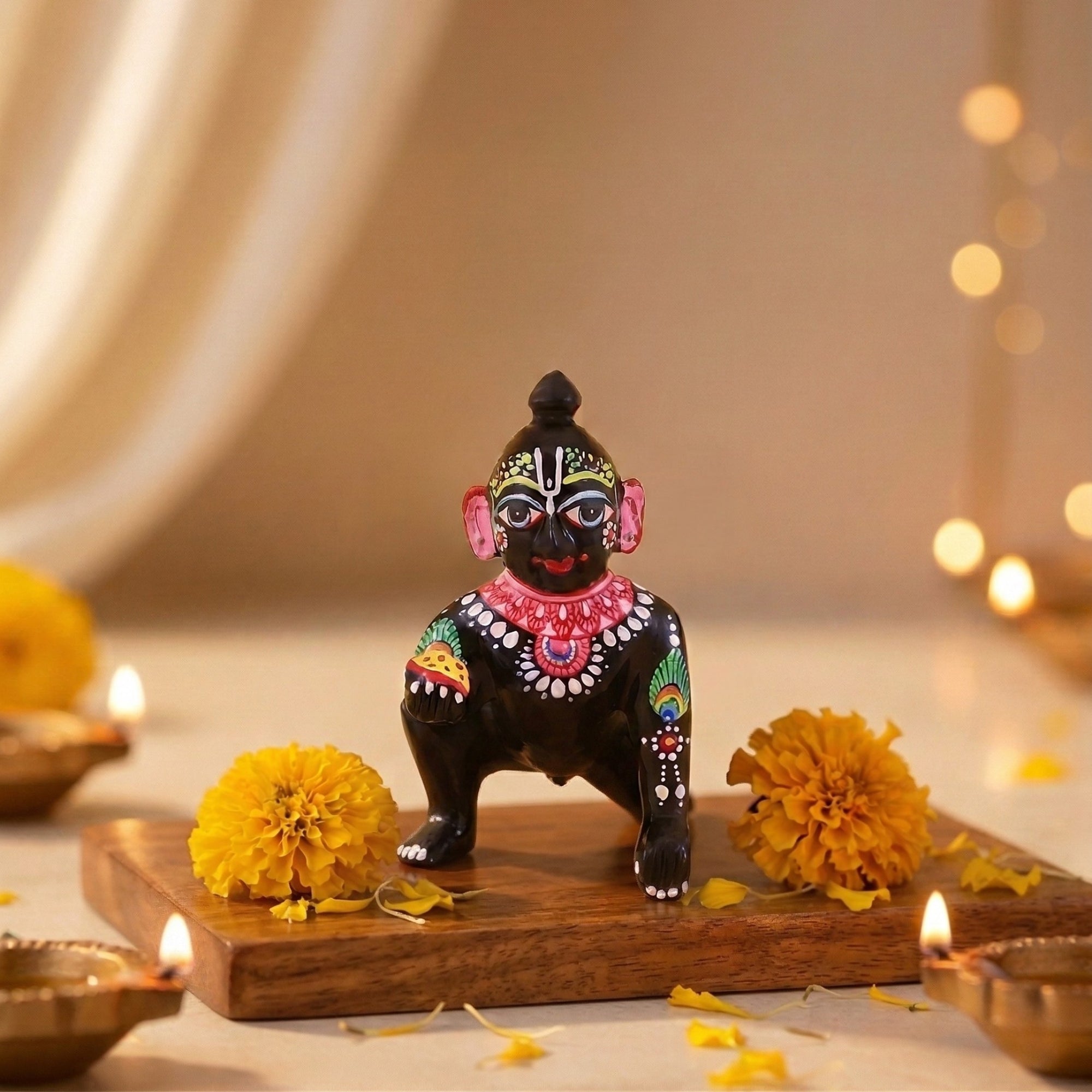 Hand-painted black brass Laddu Gopal idol with Shringar displayed with marigold flowers and diyas