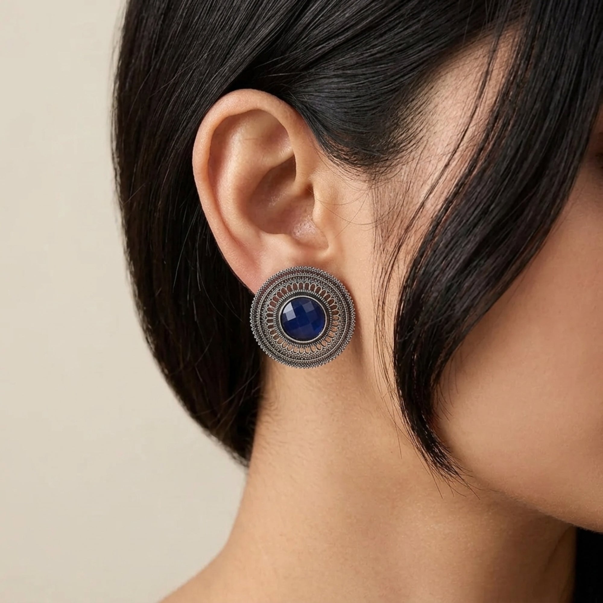Blue oxidized metal stud earring with round stone and intricate filigree design worn by woman