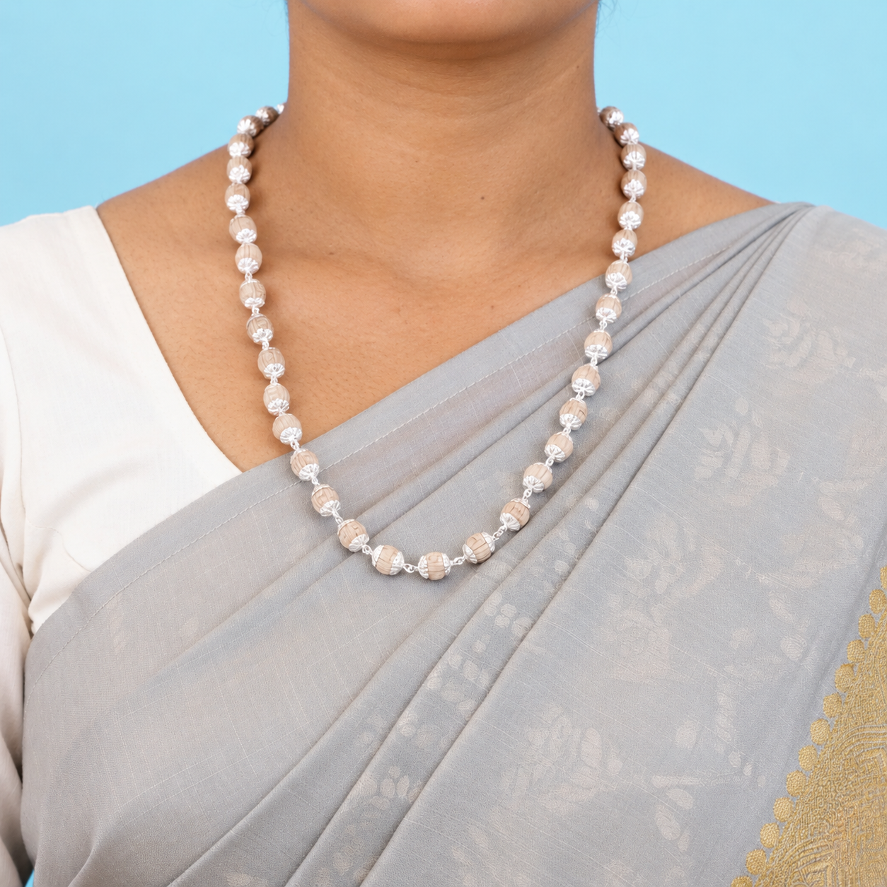 Tulsi mala with carved round wooden beads and floral silver-toned caps worn with a grey saree.