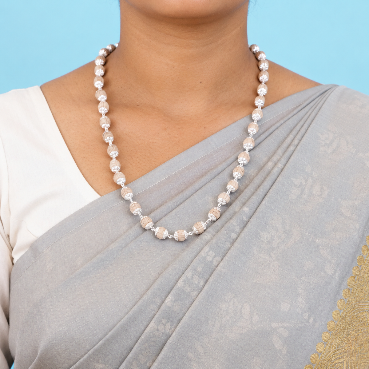 Tulsi mala with carved round wooden beads and floral silver-toned caps worn with a grey saree.