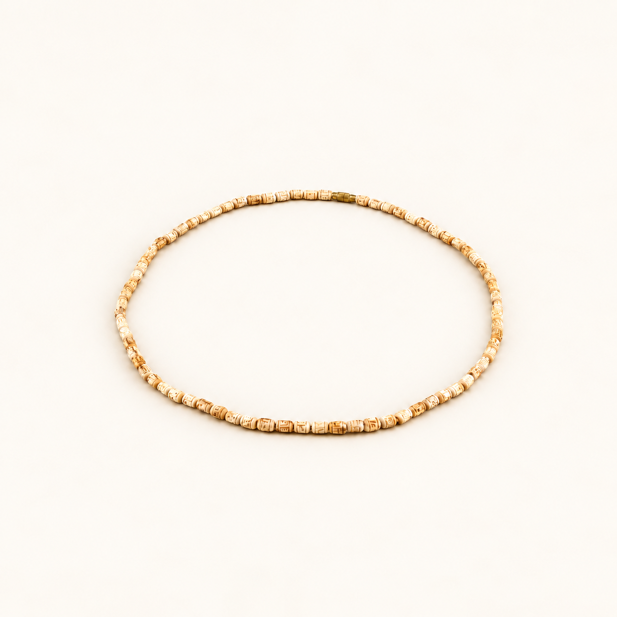 Off-white background par oval shape mein rakhi carved Tulsi bead mala.