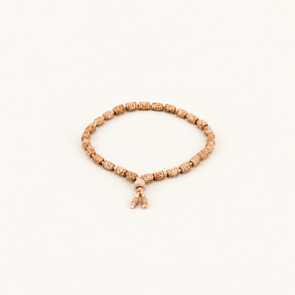 Carved Tulsi bead mala arranged in a circle with two dangling bead ends on an off-white background.