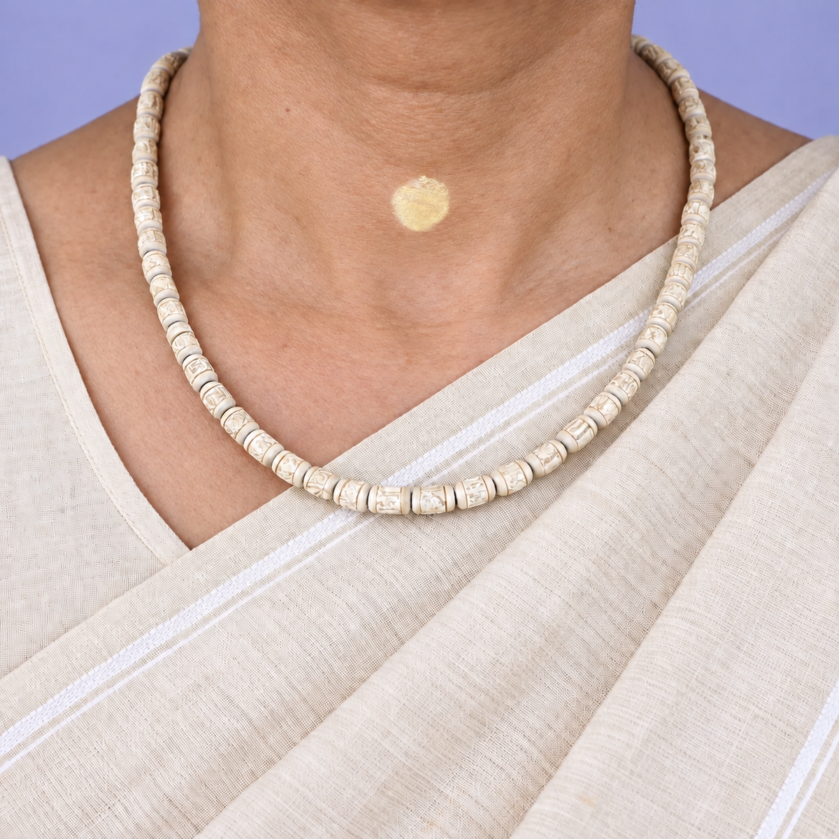 Tulsi kanthi mala with carved barrel-shaped wooden beads and disc spacers worn with a cream saree.