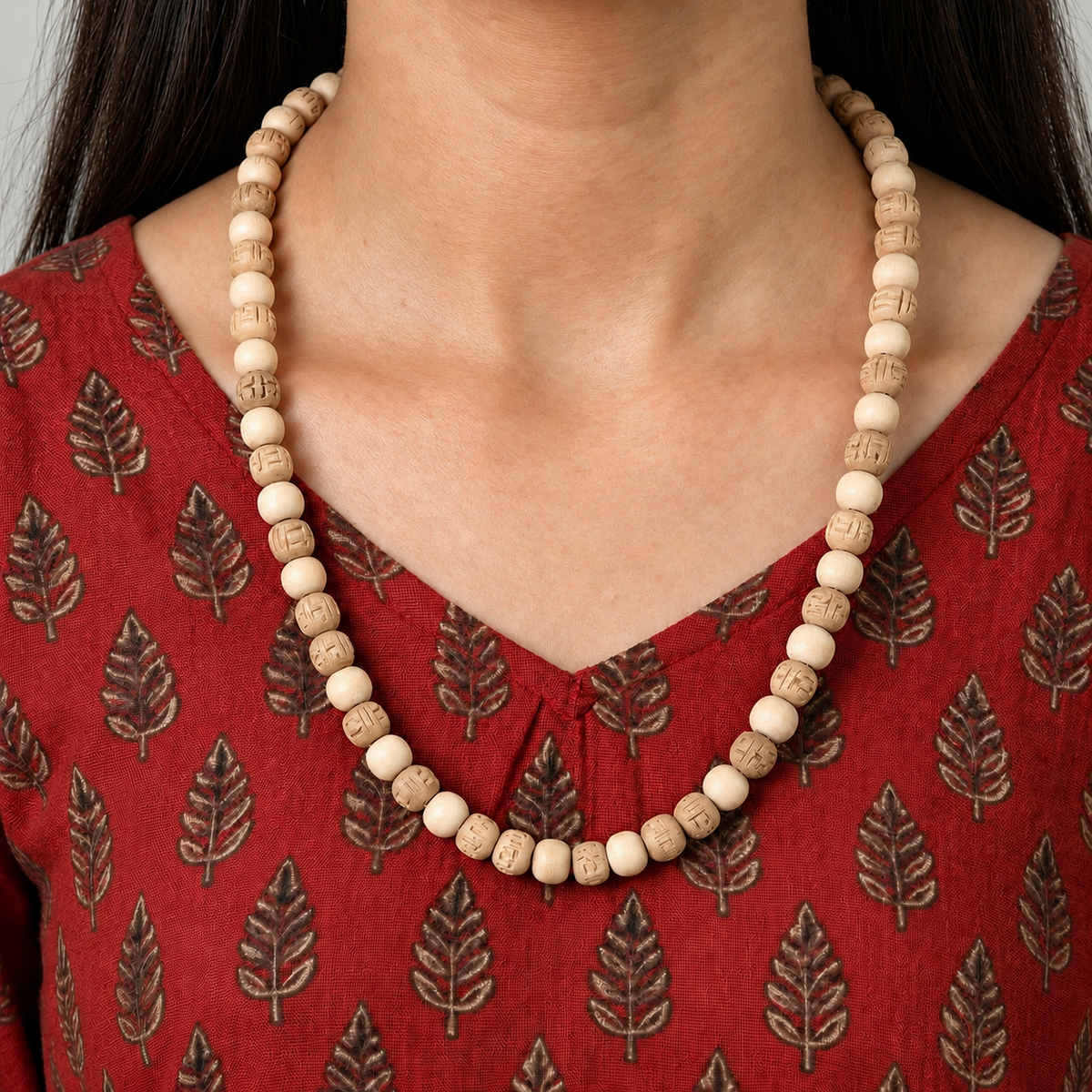 Tulsi mala with alternating plain and carved wooden beads worn with a red printed kurta.