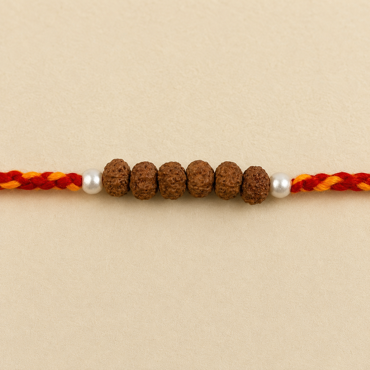 Close up view of six natural Rudraksha beads flanked by white pearl and silver spacer accents