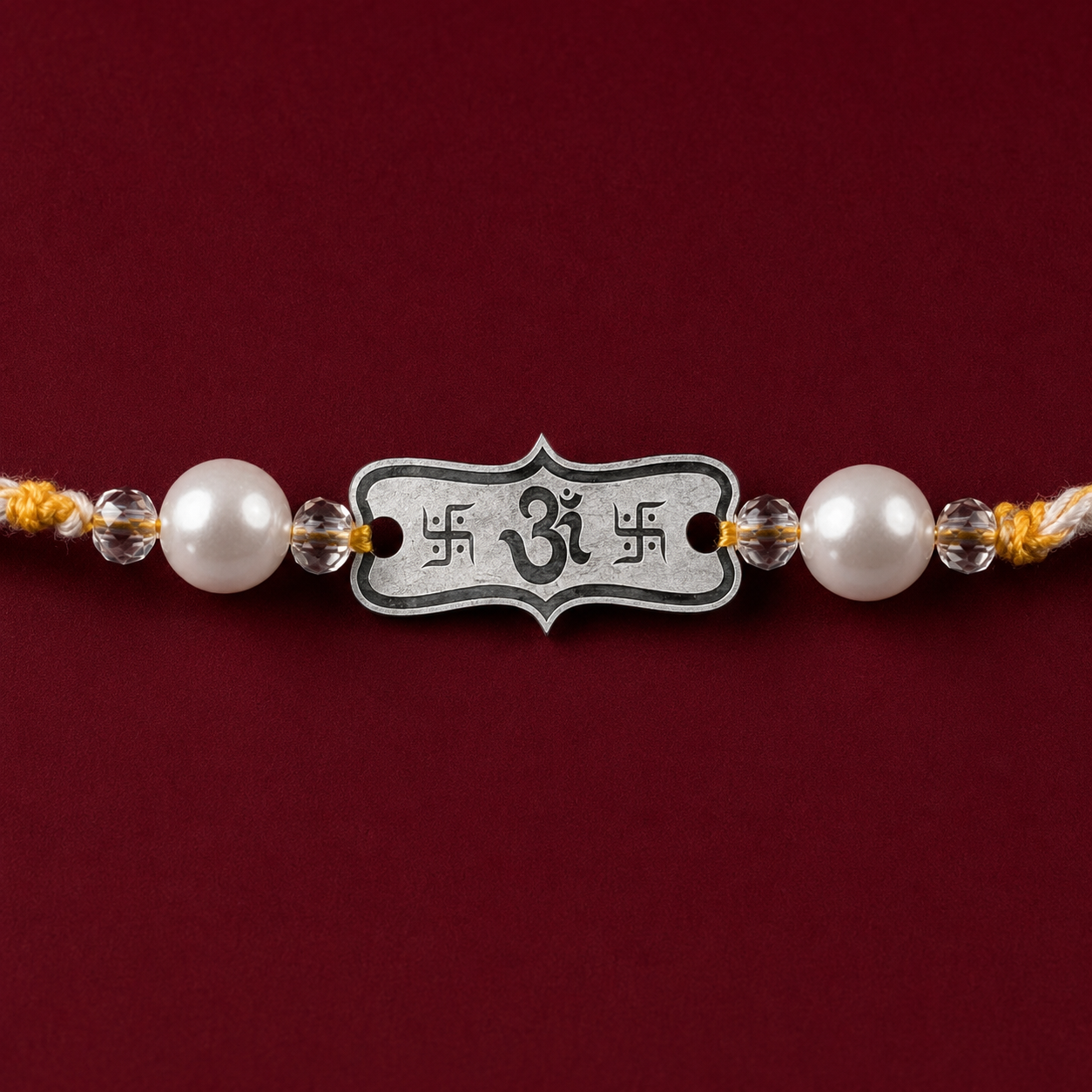 Close up view of engraved 925 sterling silver Om Subh Labh frame charm with pearl beads on maroon background