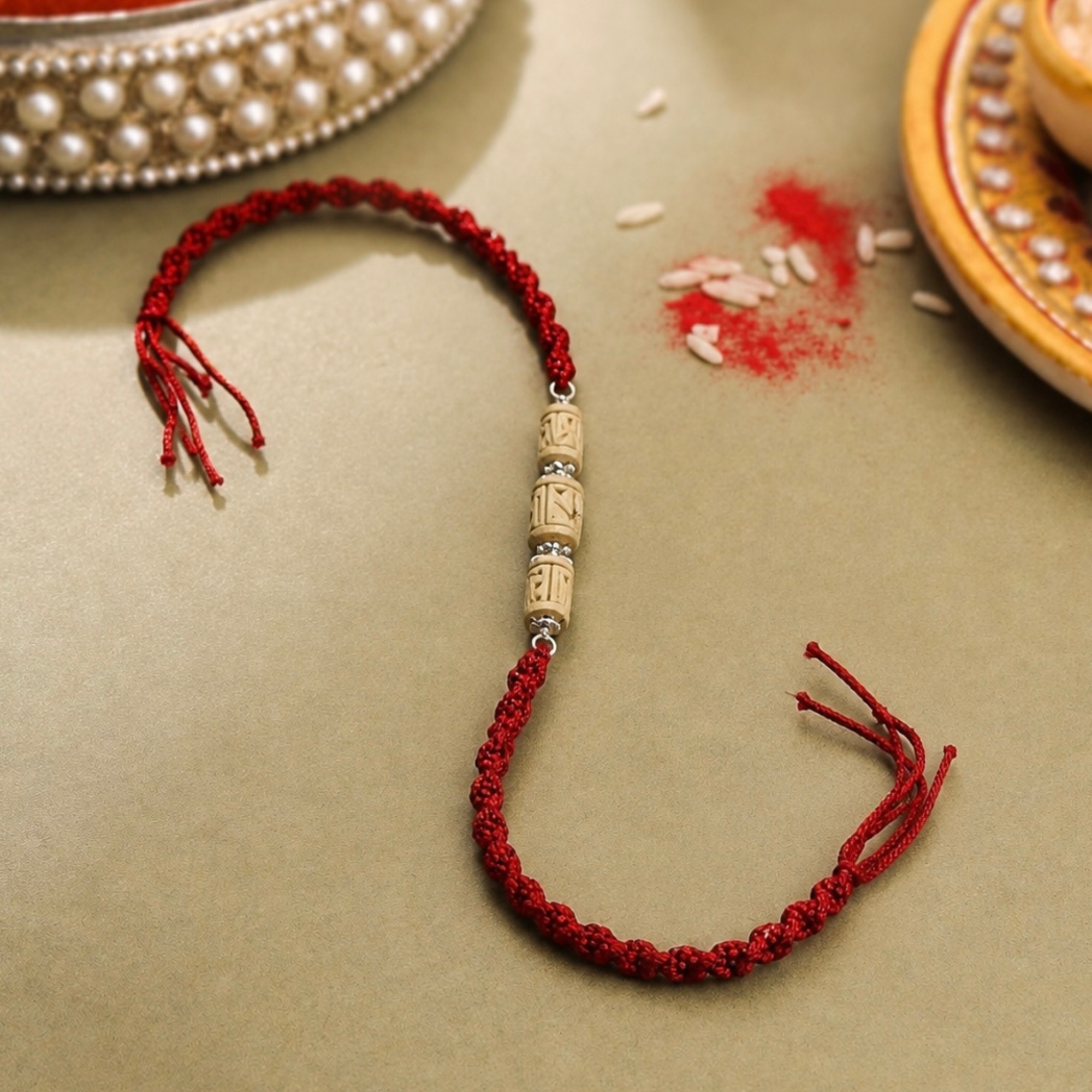 Close up view of 925 sterling silver capped carved Tulsi wood cylinder and round beads on red thread