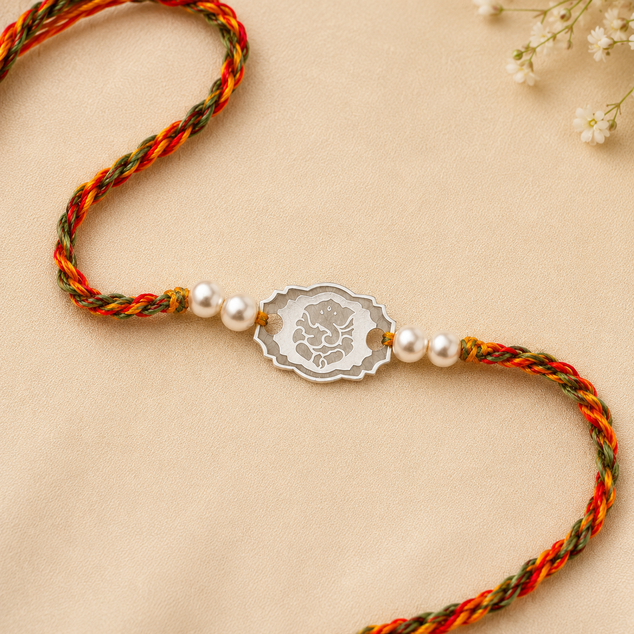Close up view of engraved 925 sterling silver oval Ganesha charm with pearl beads on multi-color thread