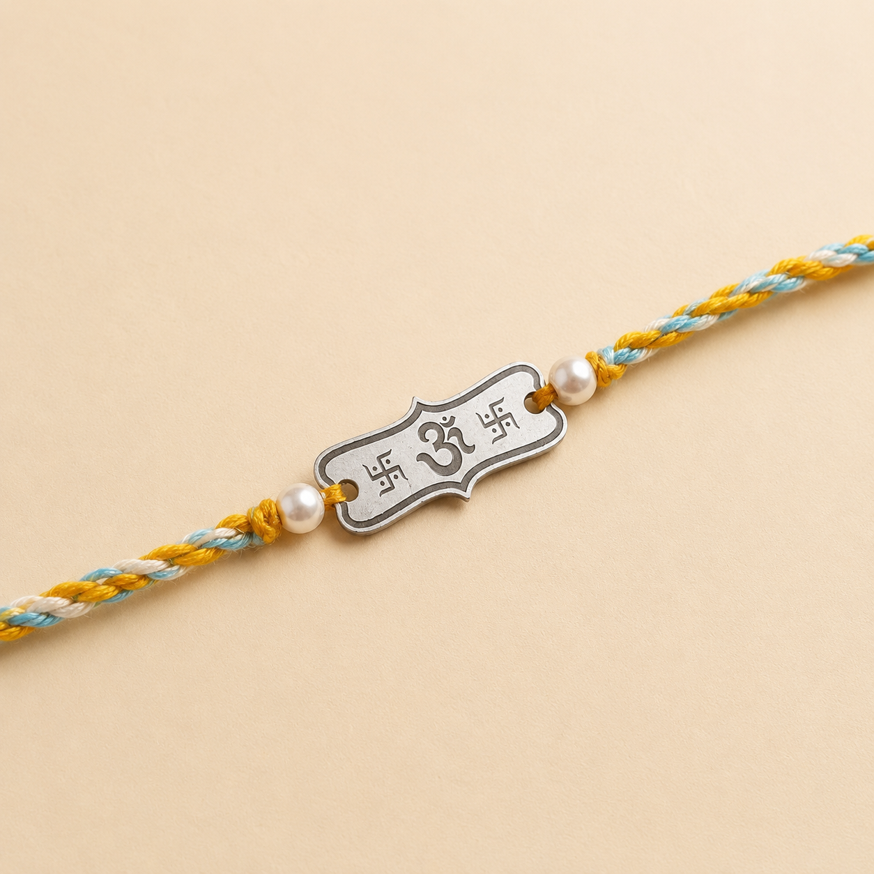 Close up view of engraved 925 sterling silver rectangular Om bar charm with pearl beads on yellow thread