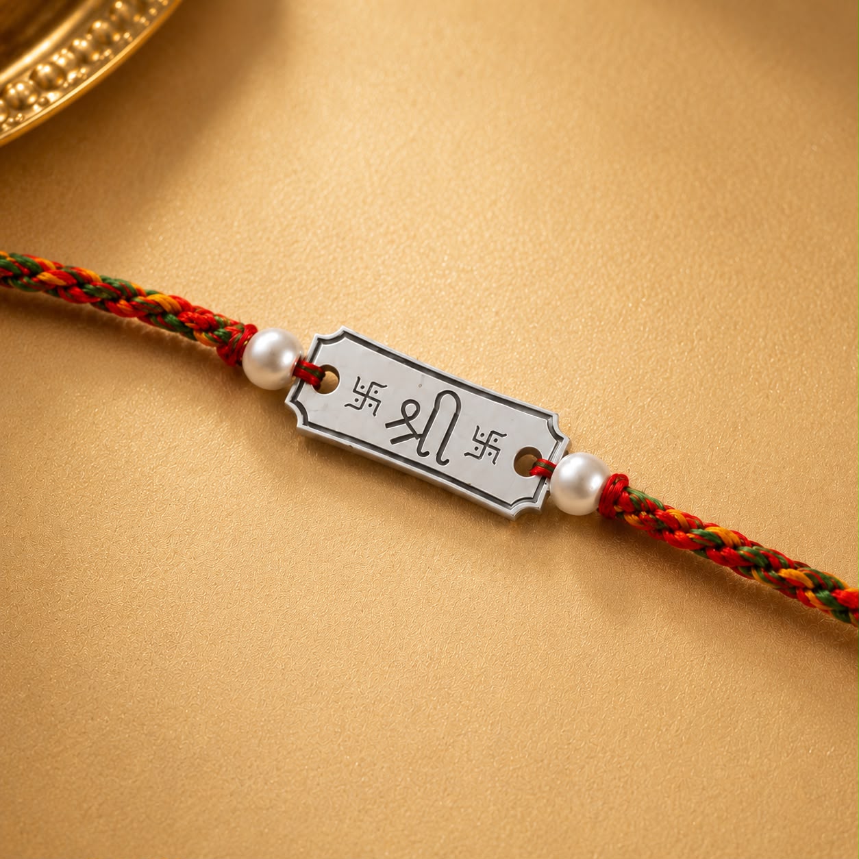 Close up view of engraved 925 sterling silver Shree Swastik charm with pearl beads on red yellow thread