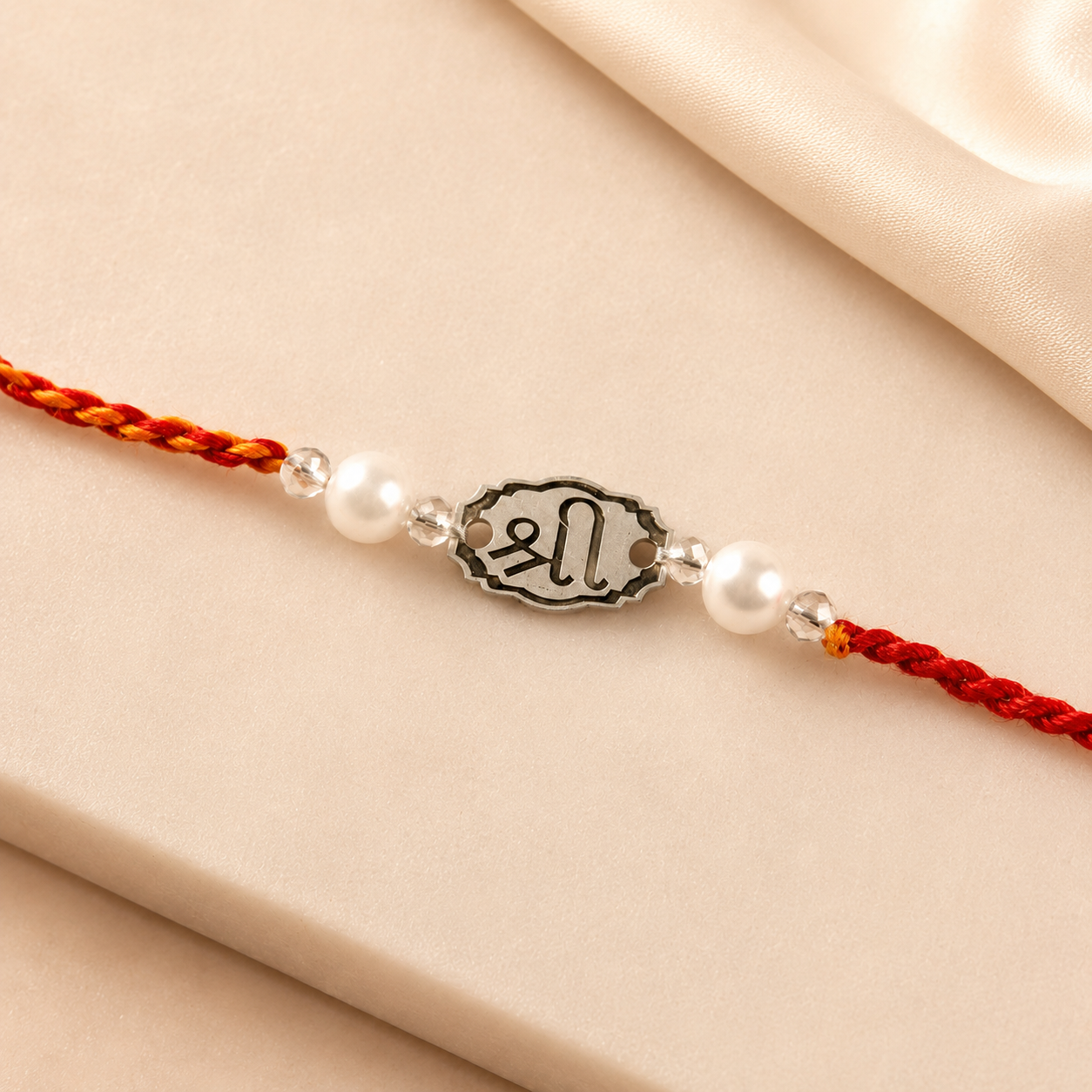 Close up view of engraved 925 sterling silver Shree symbol oval charm with pearl beads on red thread