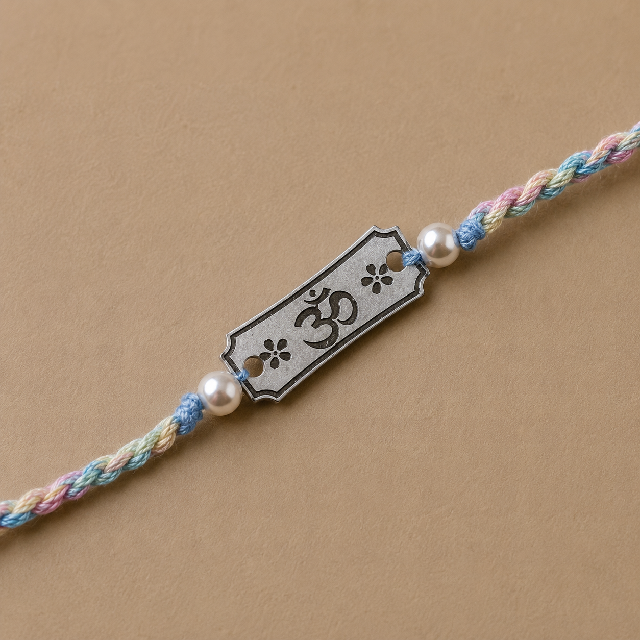 Close up view of engraved 925 sterling silver Subh Om Labh charm with pearl beads on sky blue thread