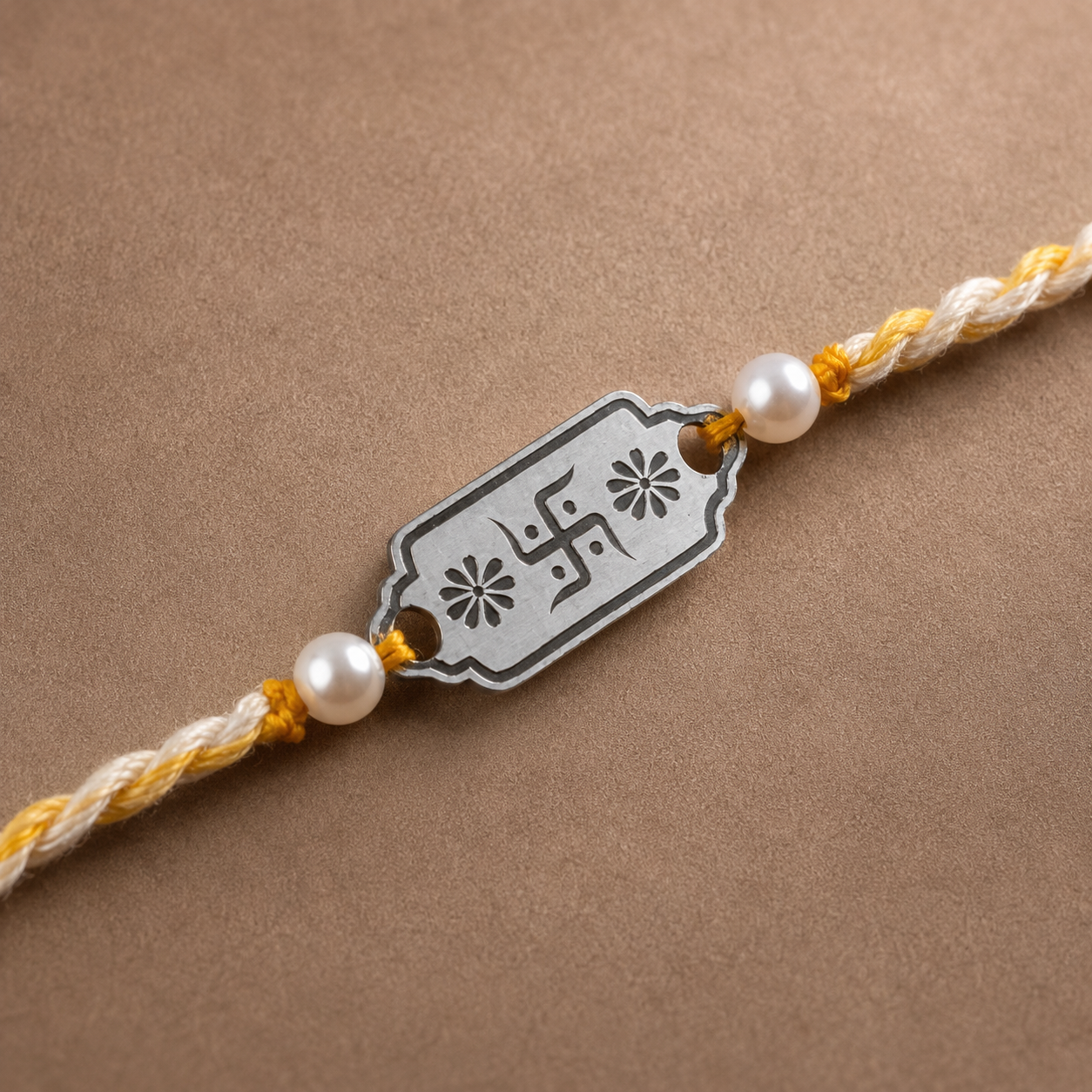 Close up view of engraved 925 sterling silver Swastik floral border charm with pearl beads on yellow thread