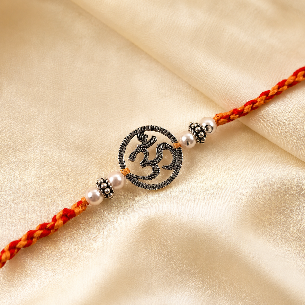 Close up view of Chandi sterling silver circular Om charm with silver beads on red yellow thread