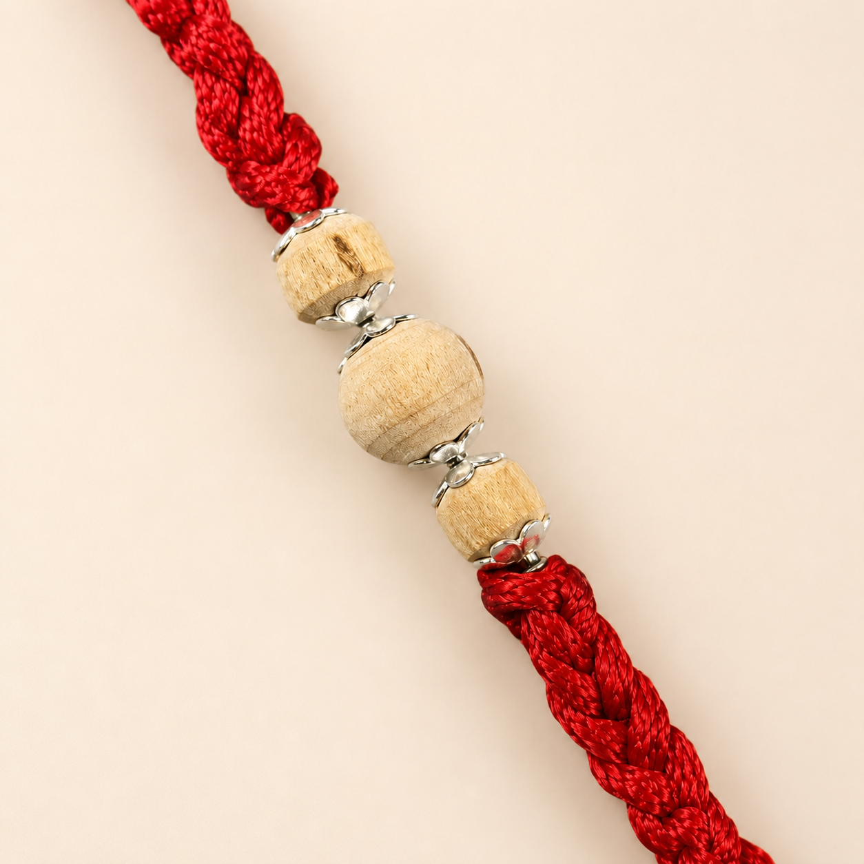 Close up view of pure silver spacer accents with three round natural Tulsi wood beads on red thread