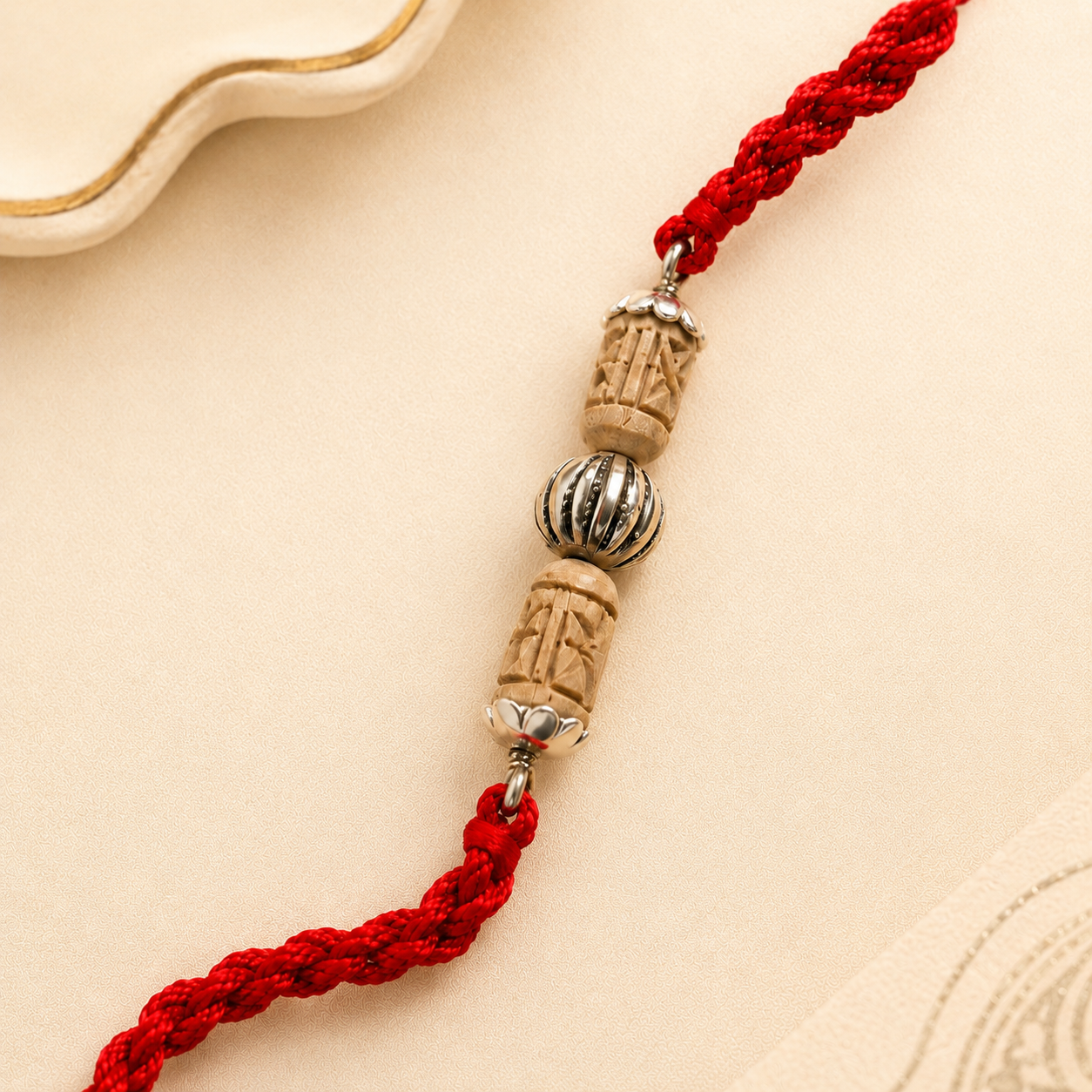 Close up view of 925 sterling silver capped floral carved Tulsi wood bead on red thread