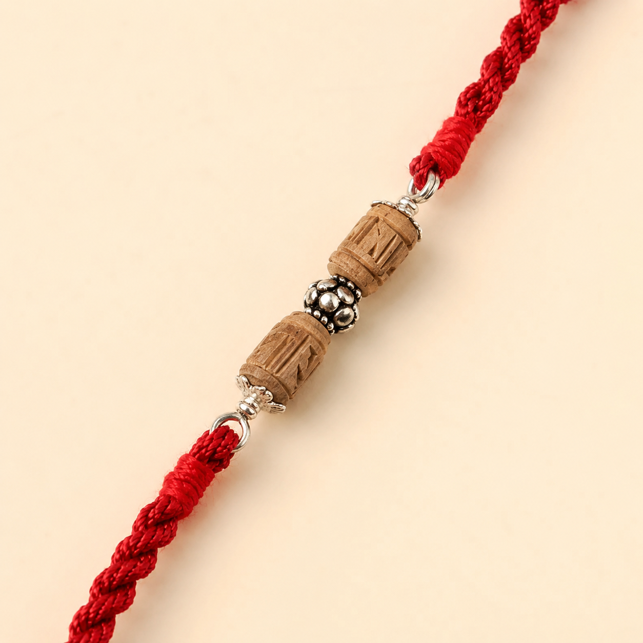 Close up view of 925 sterling silver capped carved Tulsi wood cylinder bead on red thread